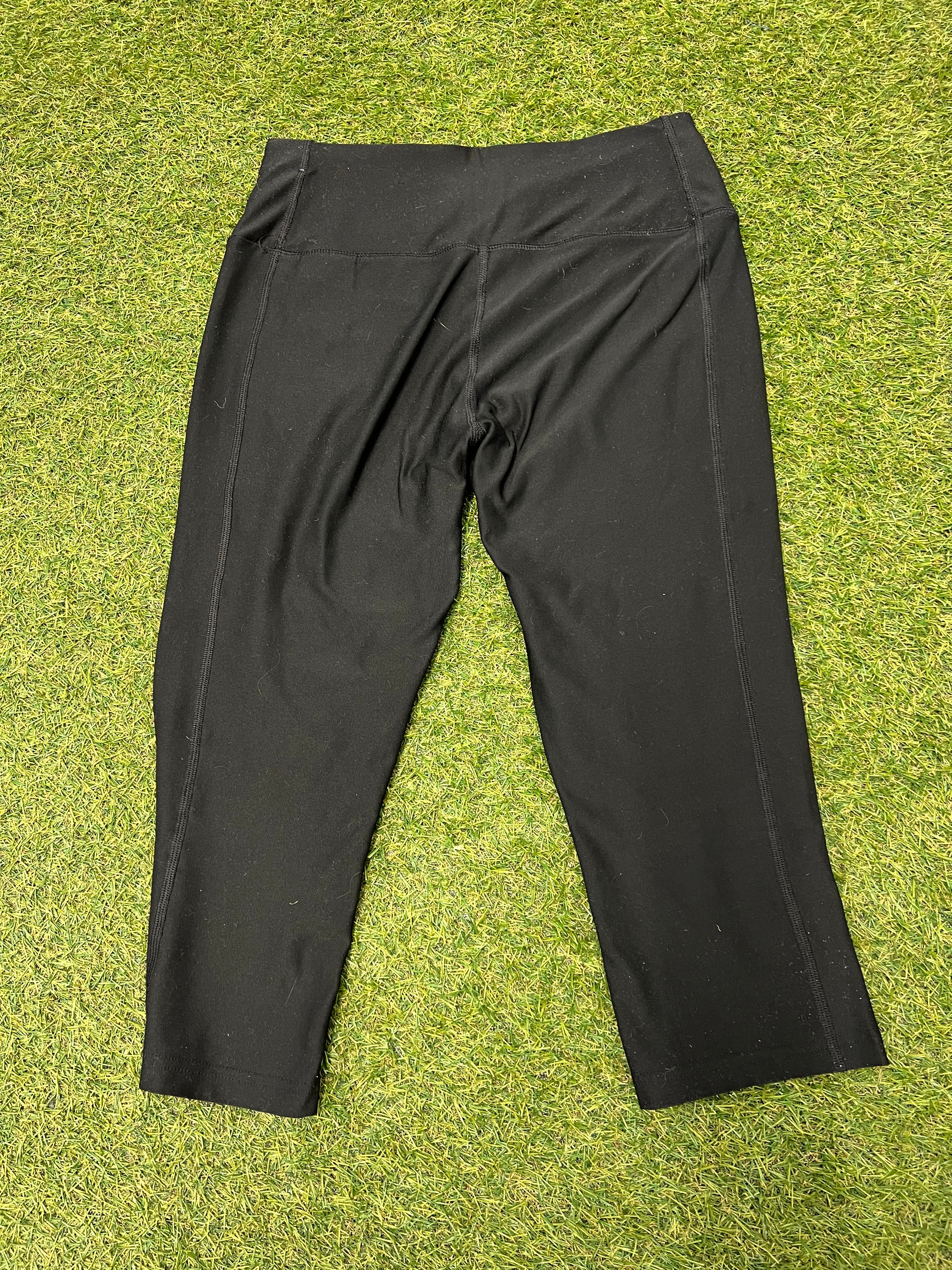 Back view of Nike Dri-FIT black cropped leggings laid flat on grass