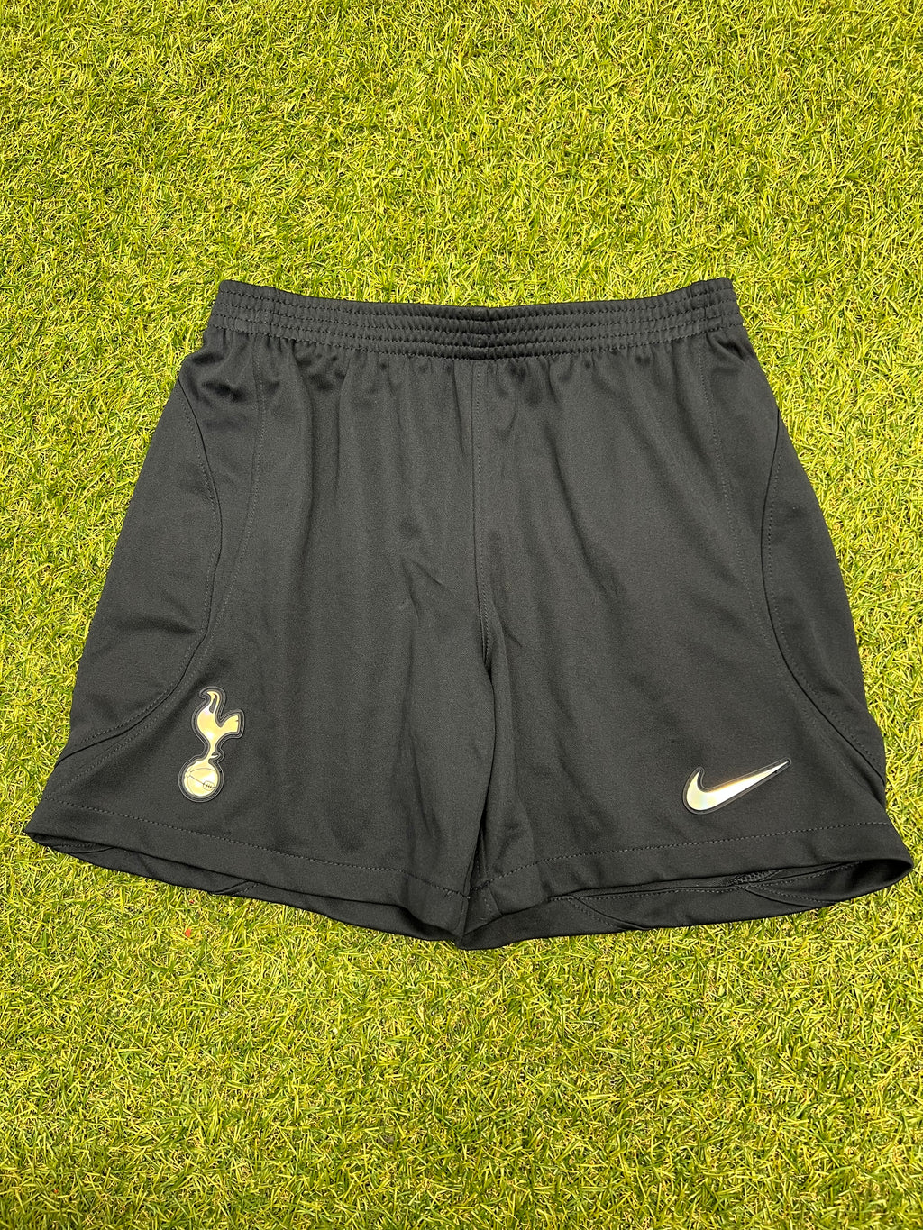 Front view of black kids Nike Tottenham Spurs shorts on grass