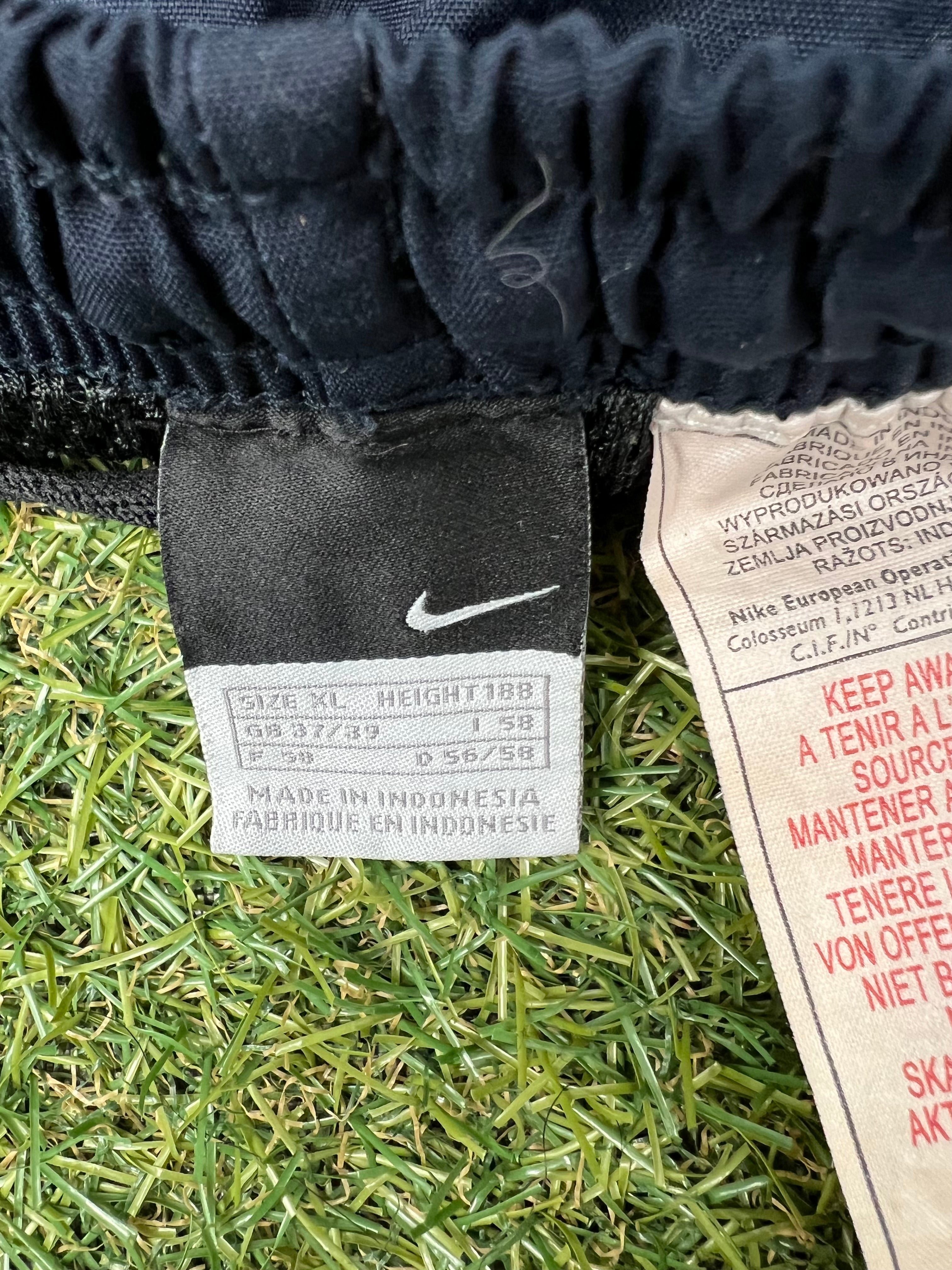 Close-up of Nike size tag inside black tracksuit trousers indicating size XL and Made in Indonesia