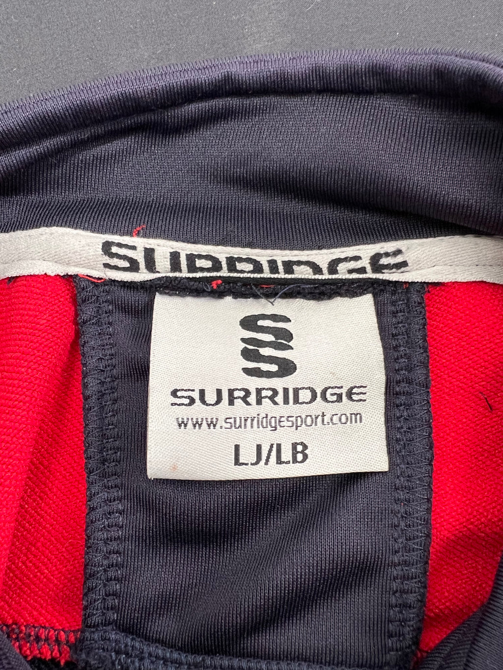 Close-up of Surridge brand label inside Essex Eagles half-zip top showing size LJ