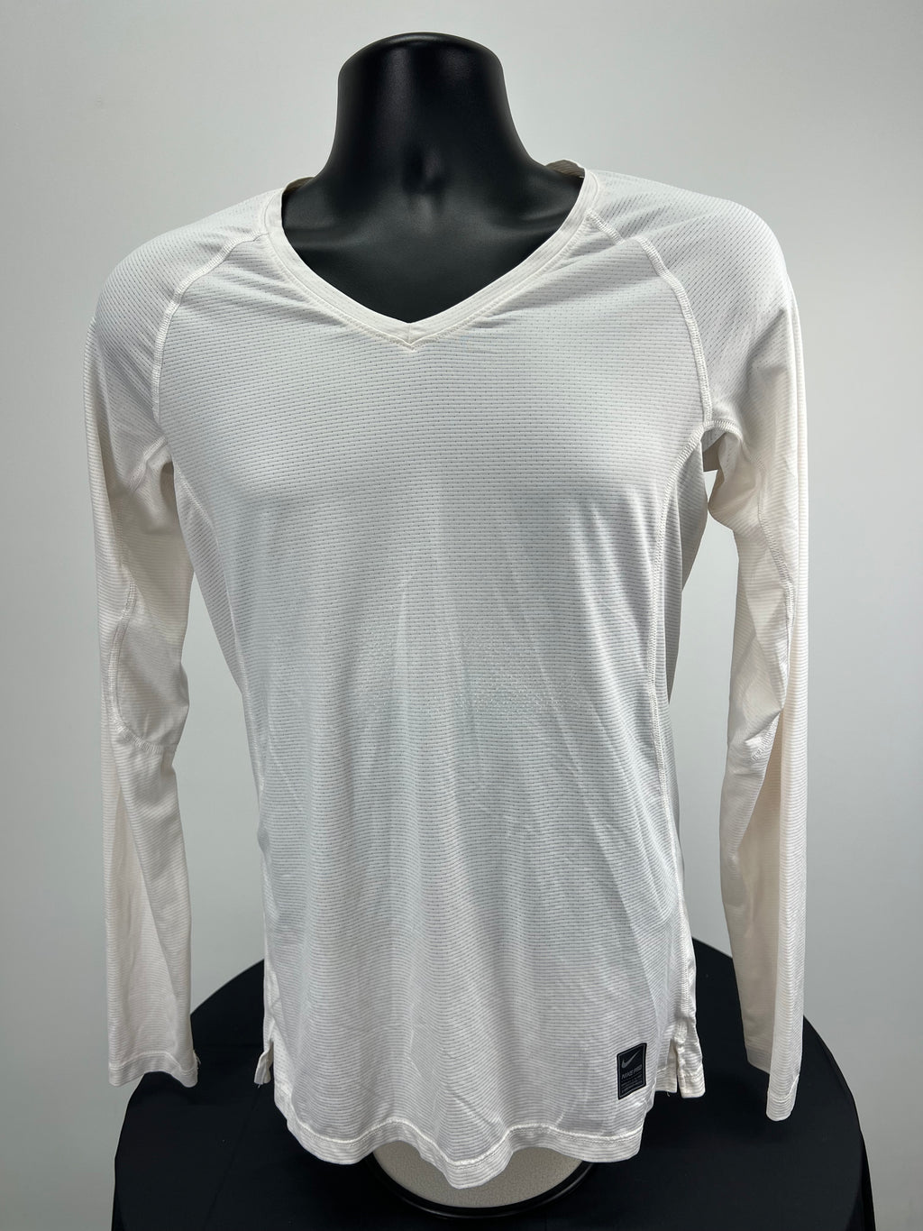 Front view of women's cream Nike Pro long sleeve V neck top on black mannequin