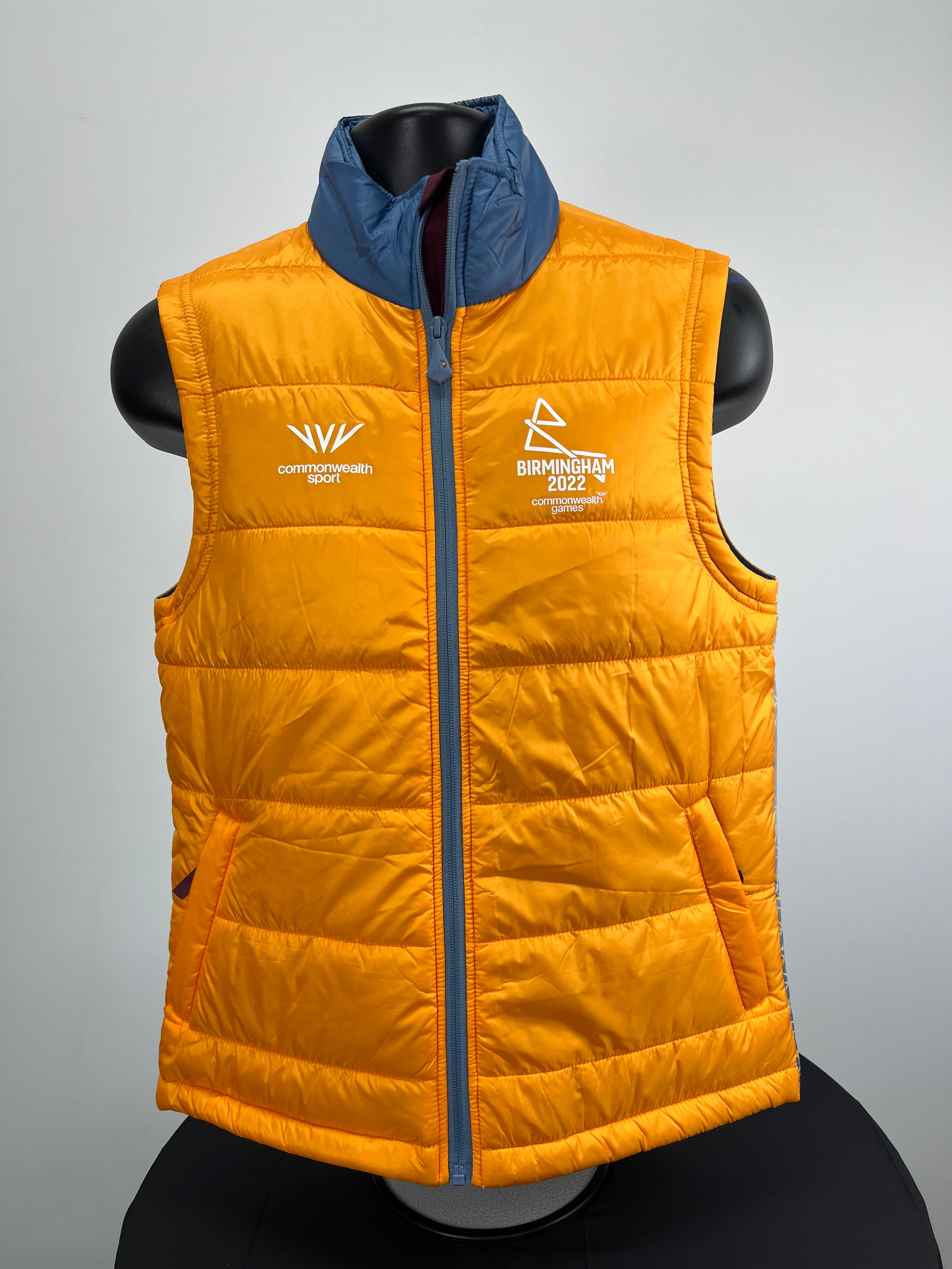 Front view of Birmingham 2022 Commonwealth Games bright orange gilet with blue collar and zip closure