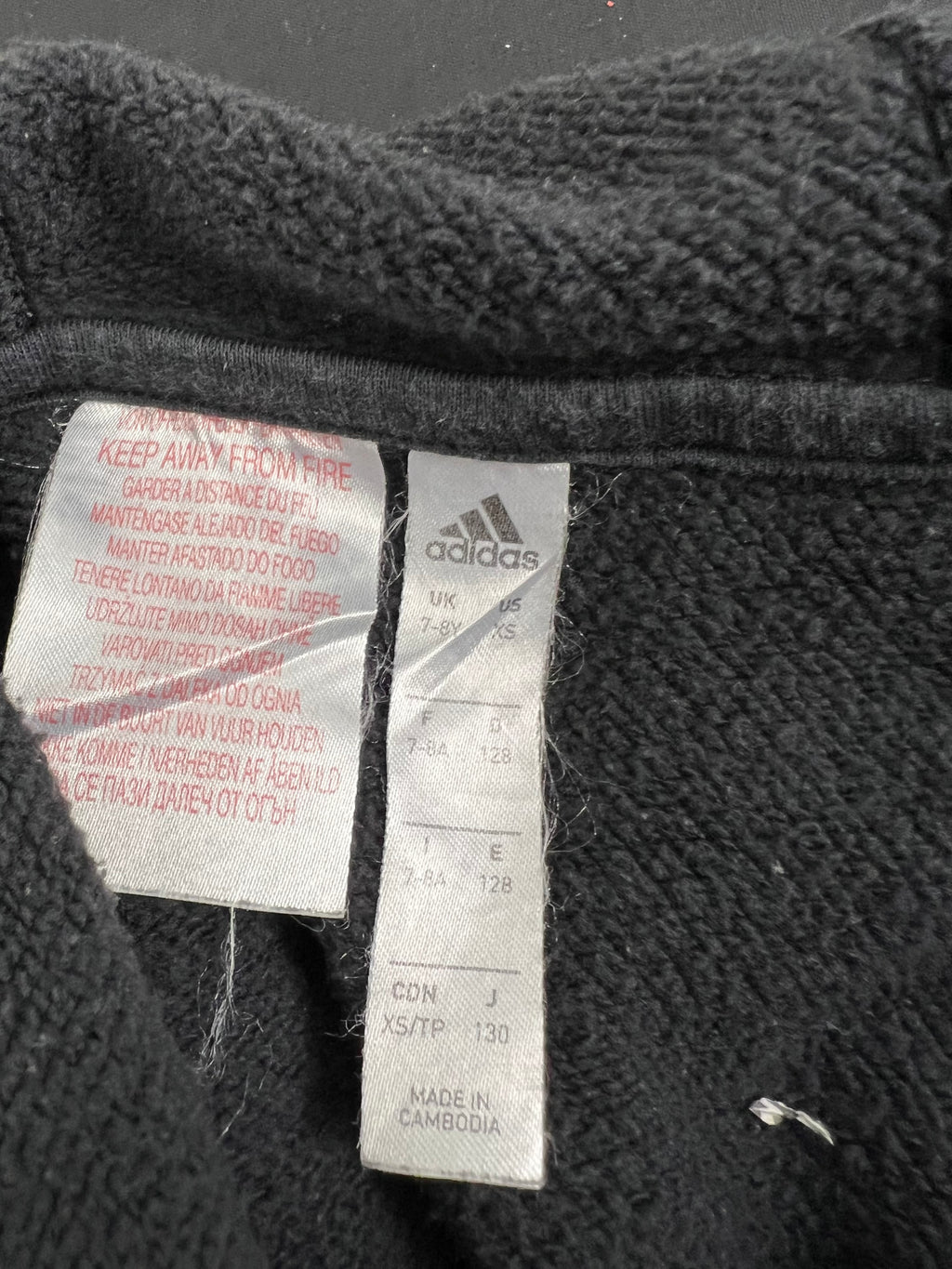 Close-up of size label inside kids' adidas hoodie reading age 7-8, made in Cambodia
