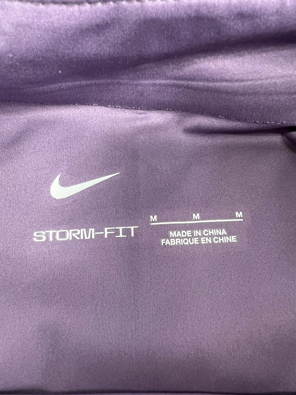 Close-up inside neck tag showing Nike Storm-FIT logo and size M
