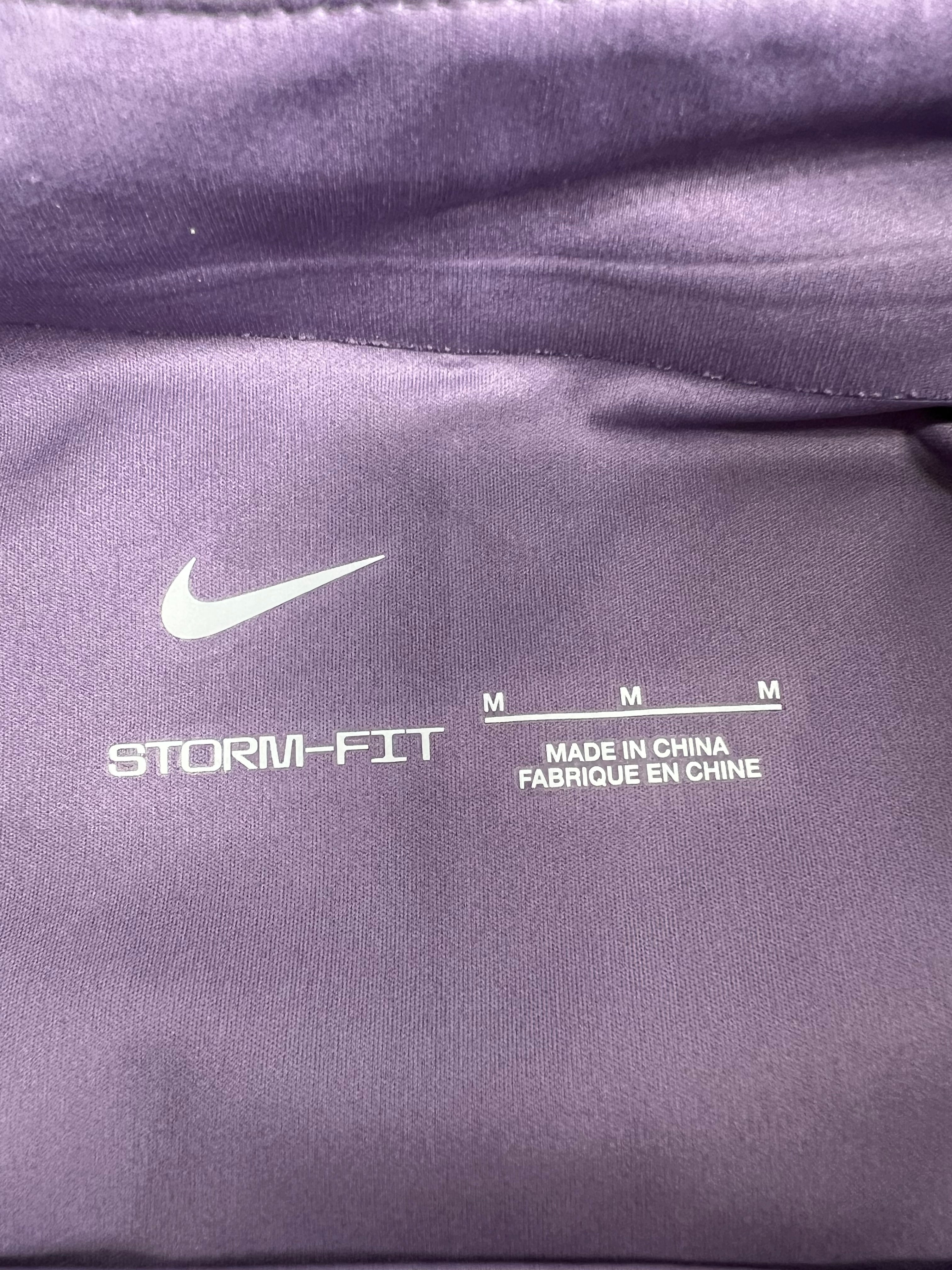 Close-up inside neck tag showing Nike Storm-FIT logo and size M