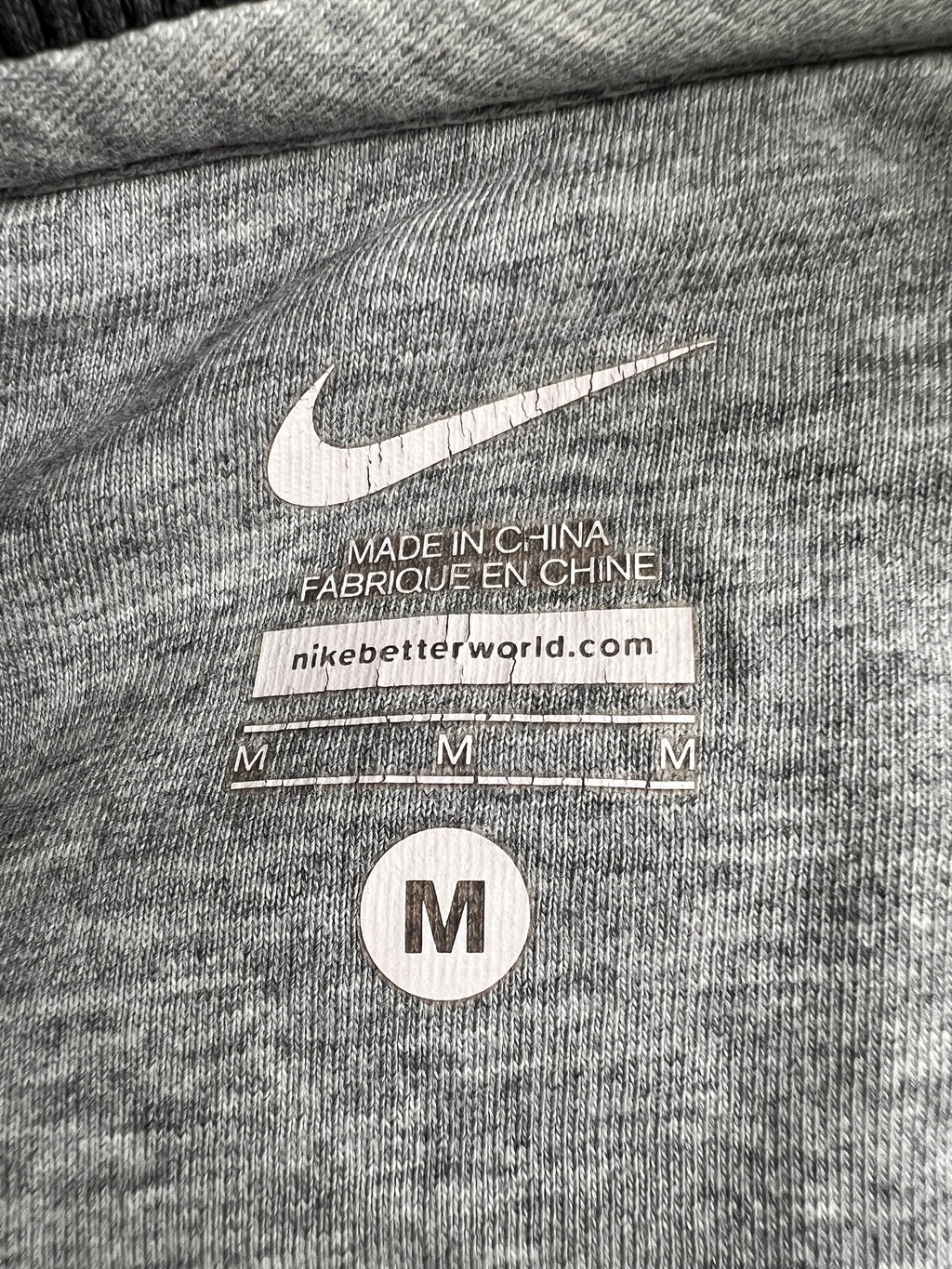 Close-up of Nike tag and size medium label printed inside the grey fabric top