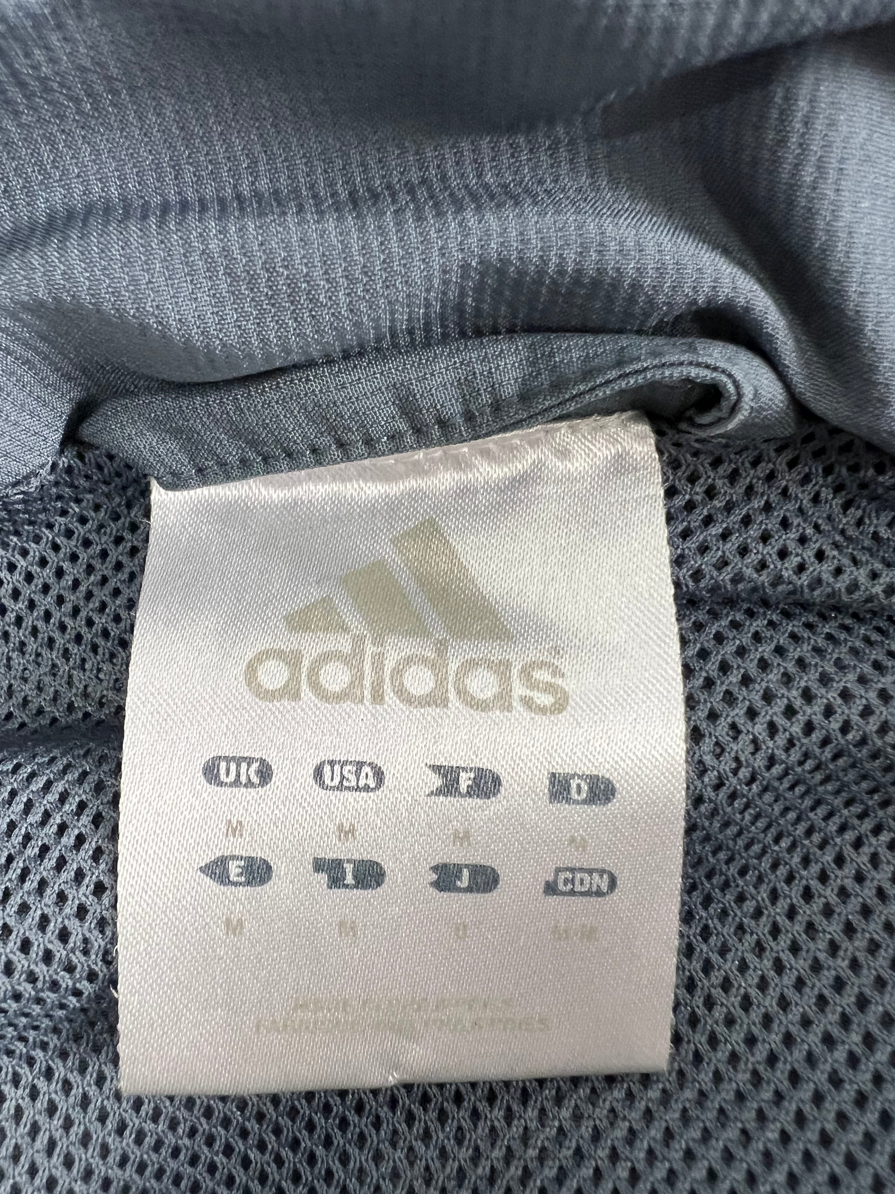 Close-up of Adidas size tag inside the grey half zip top showing size Medium