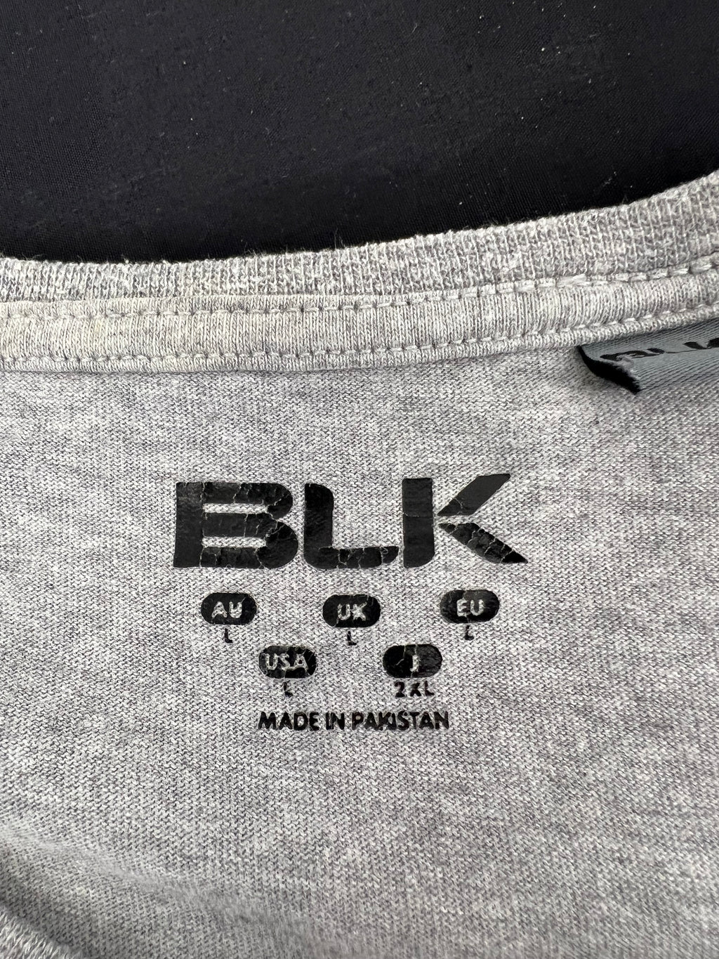 Close-up of black BLK brand logo printed inside collar area of the grey Exiles t-shirt