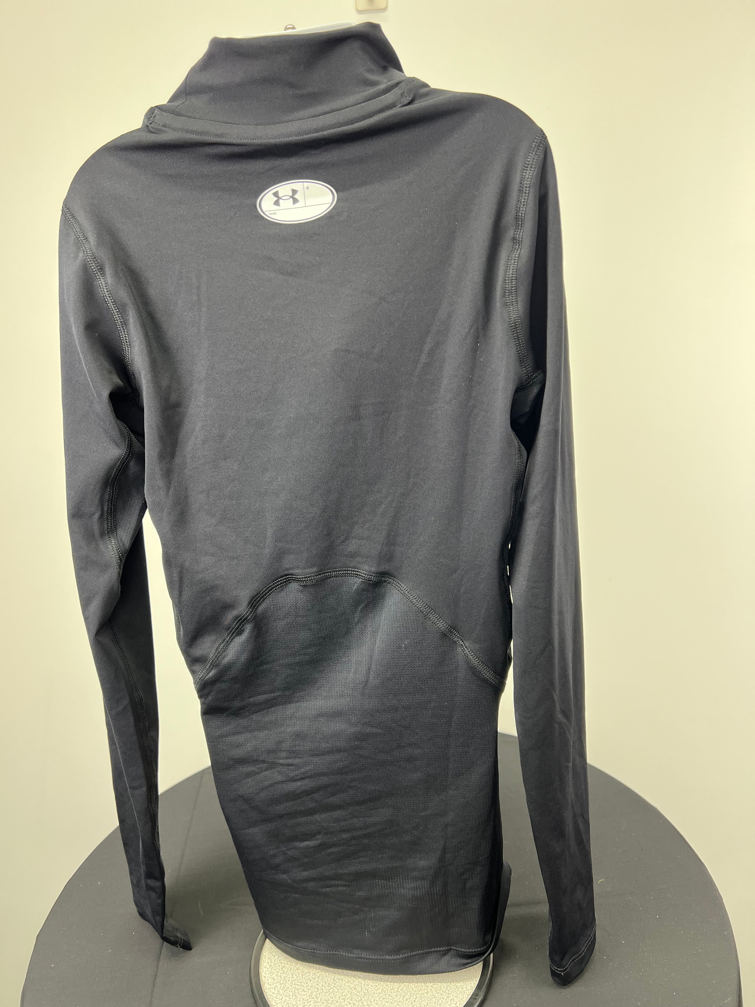 Back view of black Under Armour compression top showing high collar and fabric texture