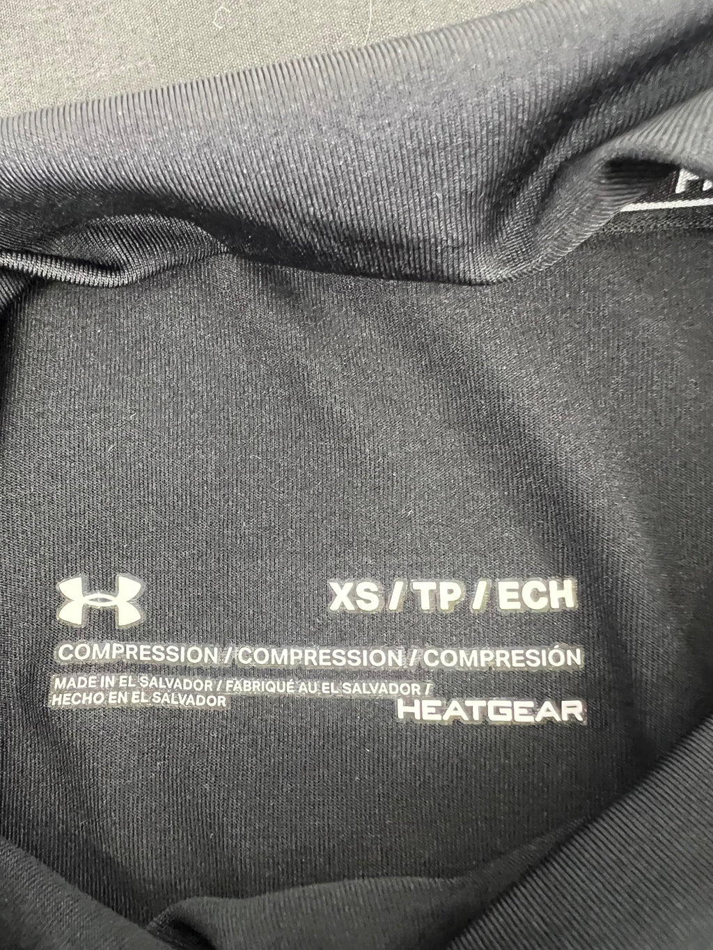 Close-up of the inner label displaying Under Armour logo, XS size, Compression and HeatGear branding