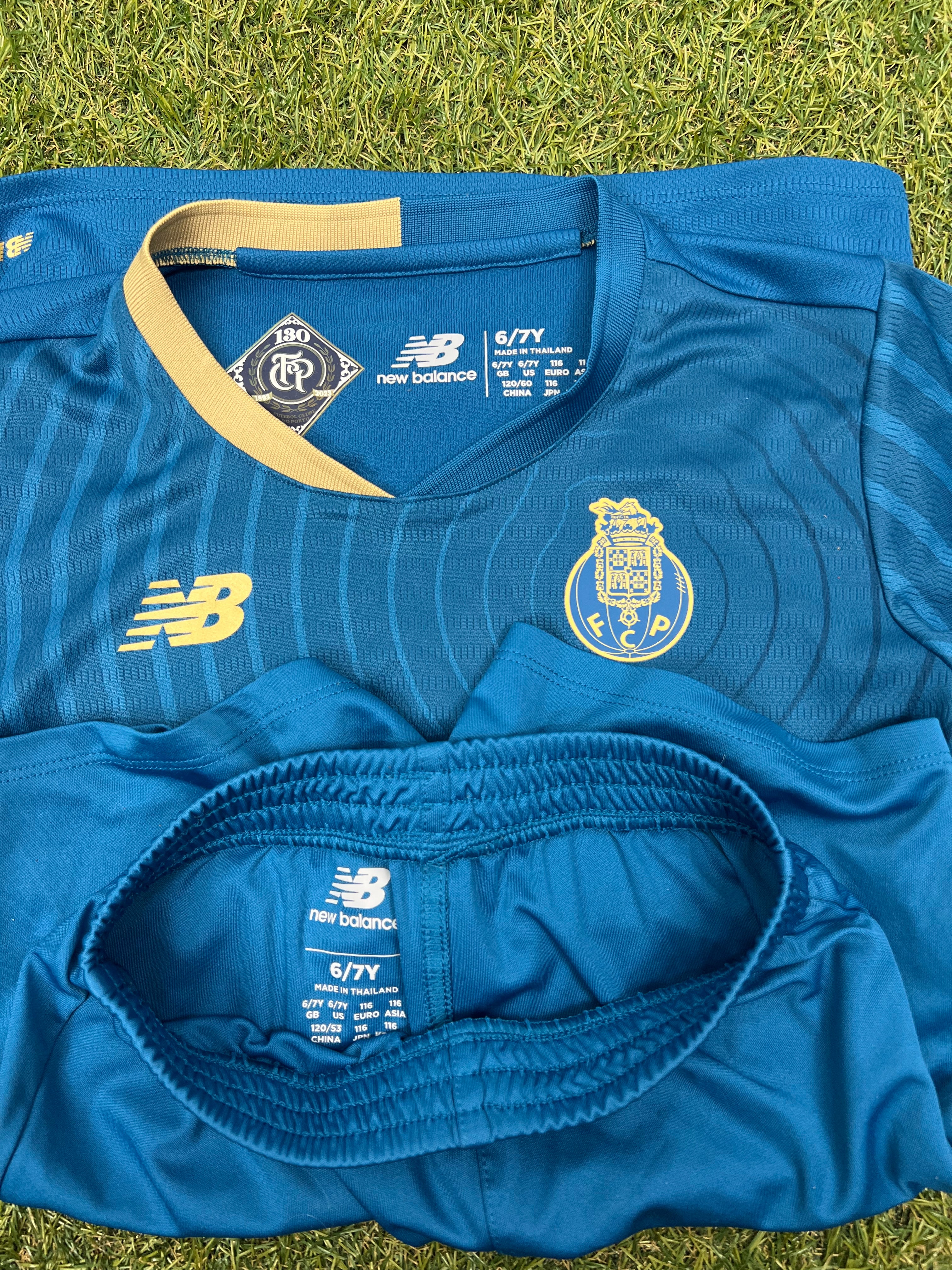 Close-up of neckline and waistband tags showing New Balance branding and size information of kids FC Porto football strip