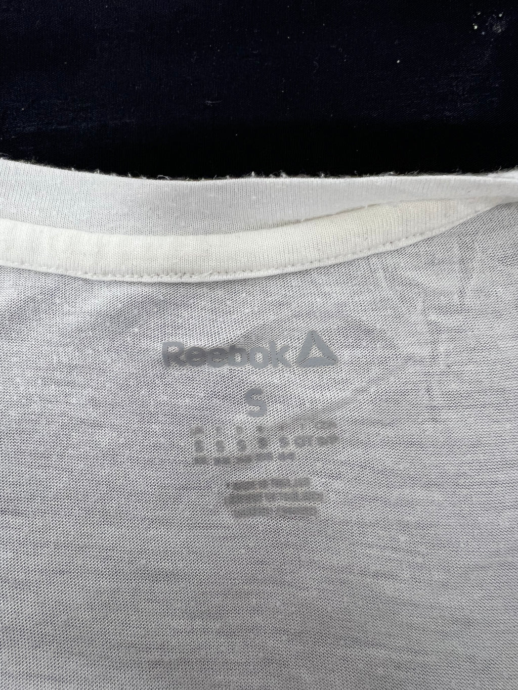 Close-up of inside neck label showing Reebok logo and size S on white Body Combat vest
