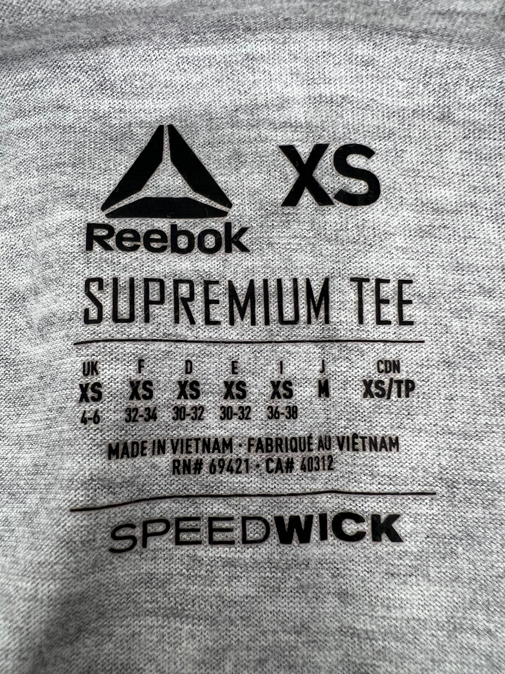 Close-up of Reebok label and size XS tag on grey sports vest with Speedwick detail