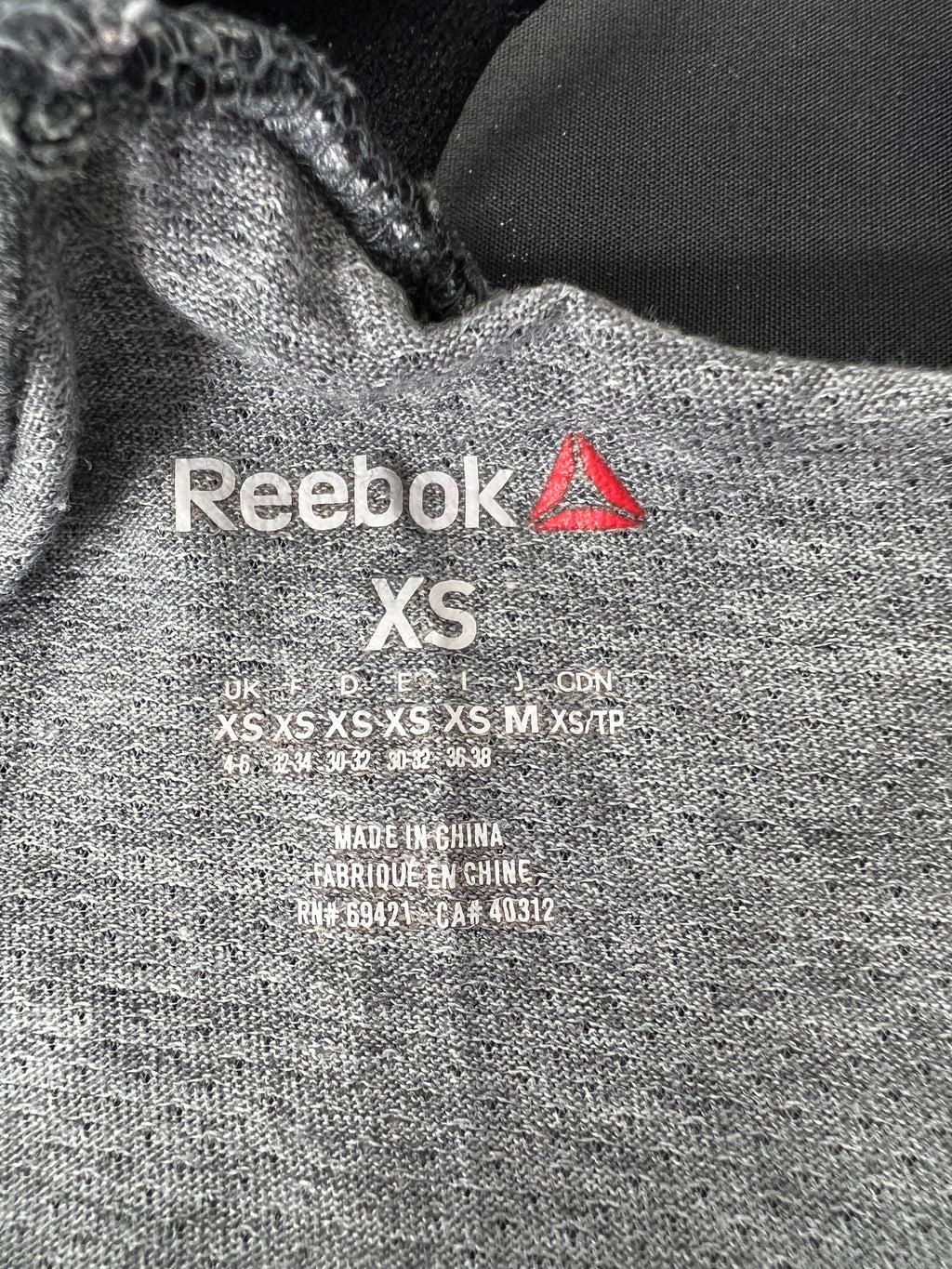 Close-up of inside label showing Reebok logo and XS size on grey fabric