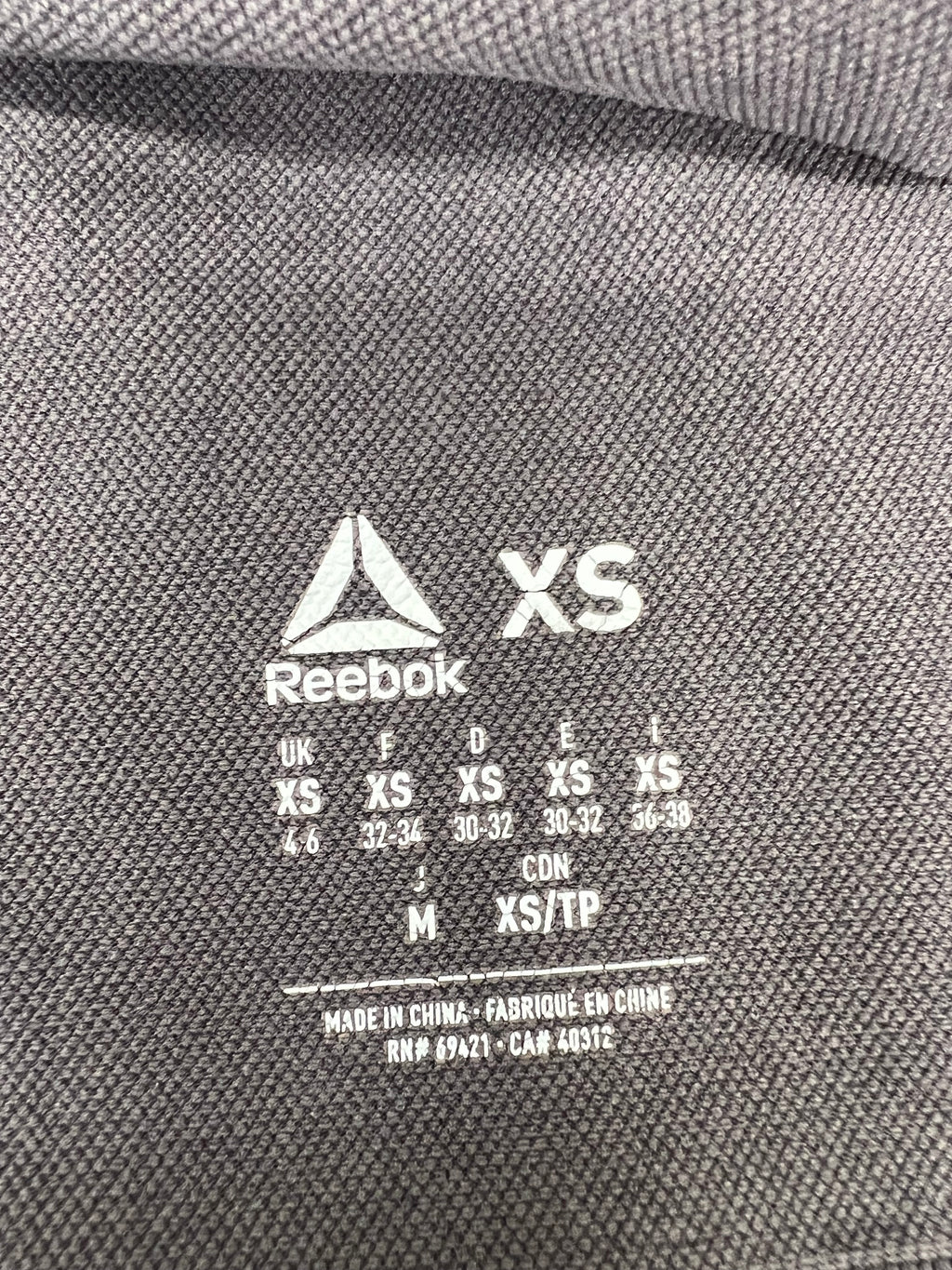 Close-up of sizing and care label on Reebok x Les Mills grey vest top size XS