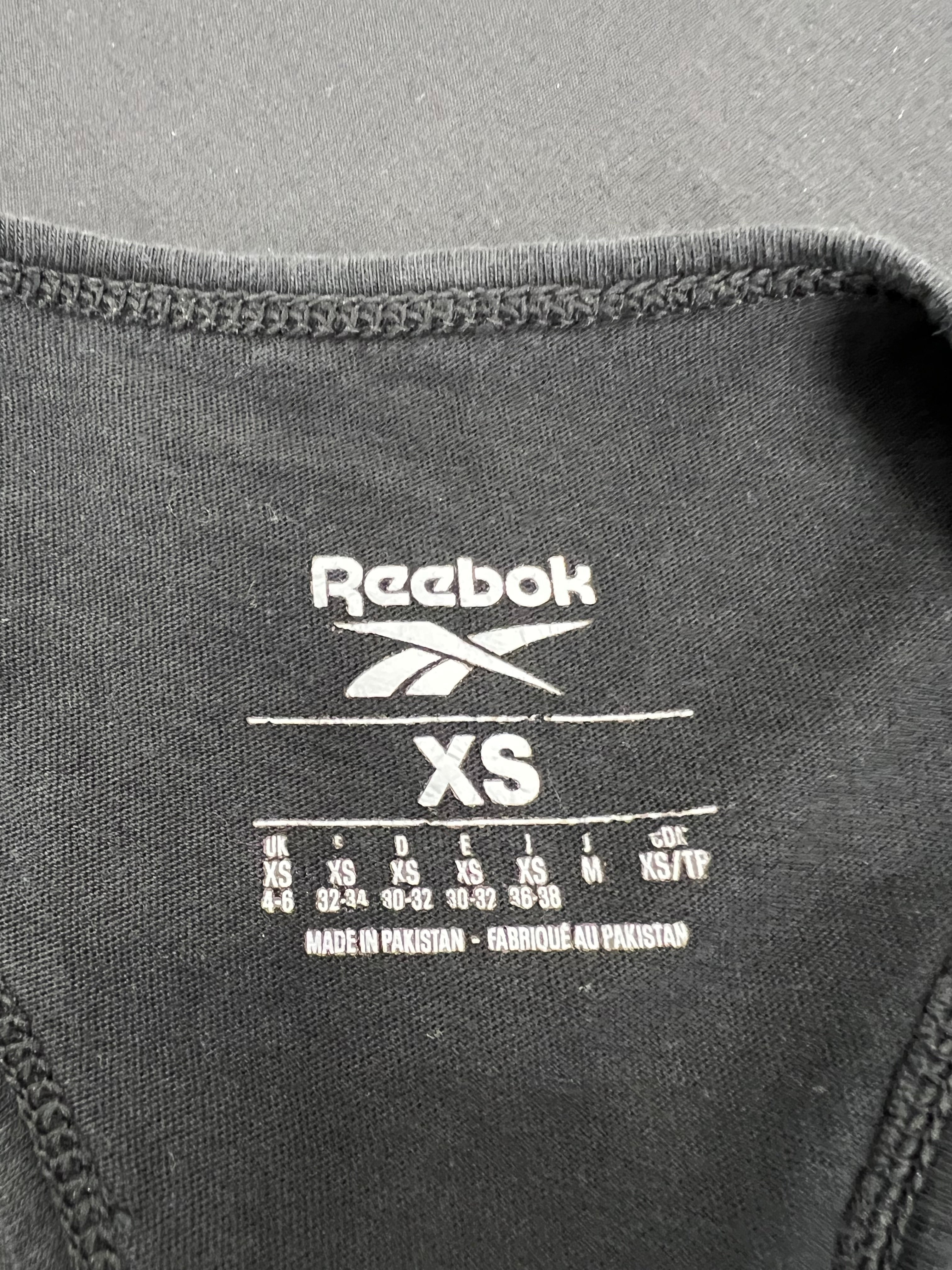 Close-up of size label inside black Reebok vest top showing XS size and manufacturing details