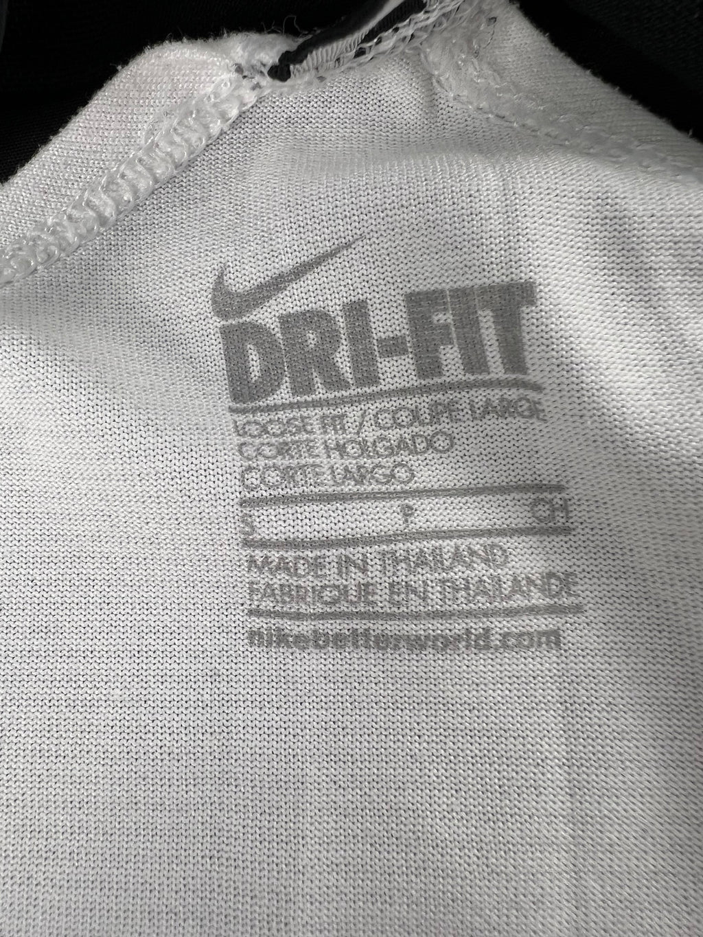 Close-up of Nike Dri-FIT fabric label inside white vest top showing size S and care info