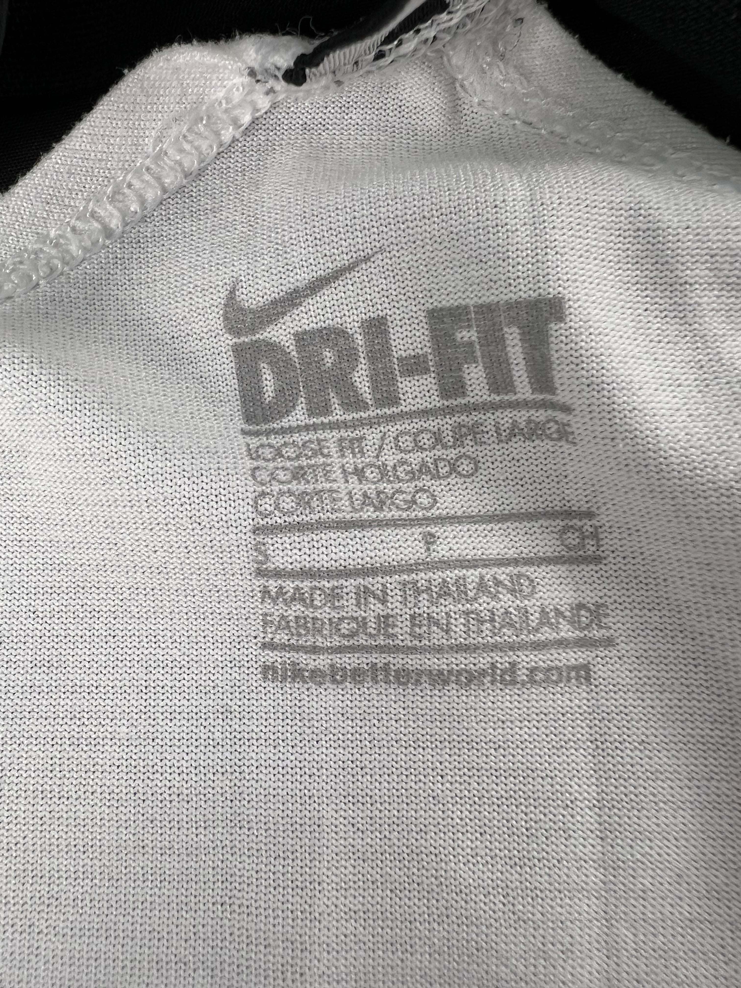 Close-up of Nike Dri-FIT fabric label inside white vest top showing size S and care info