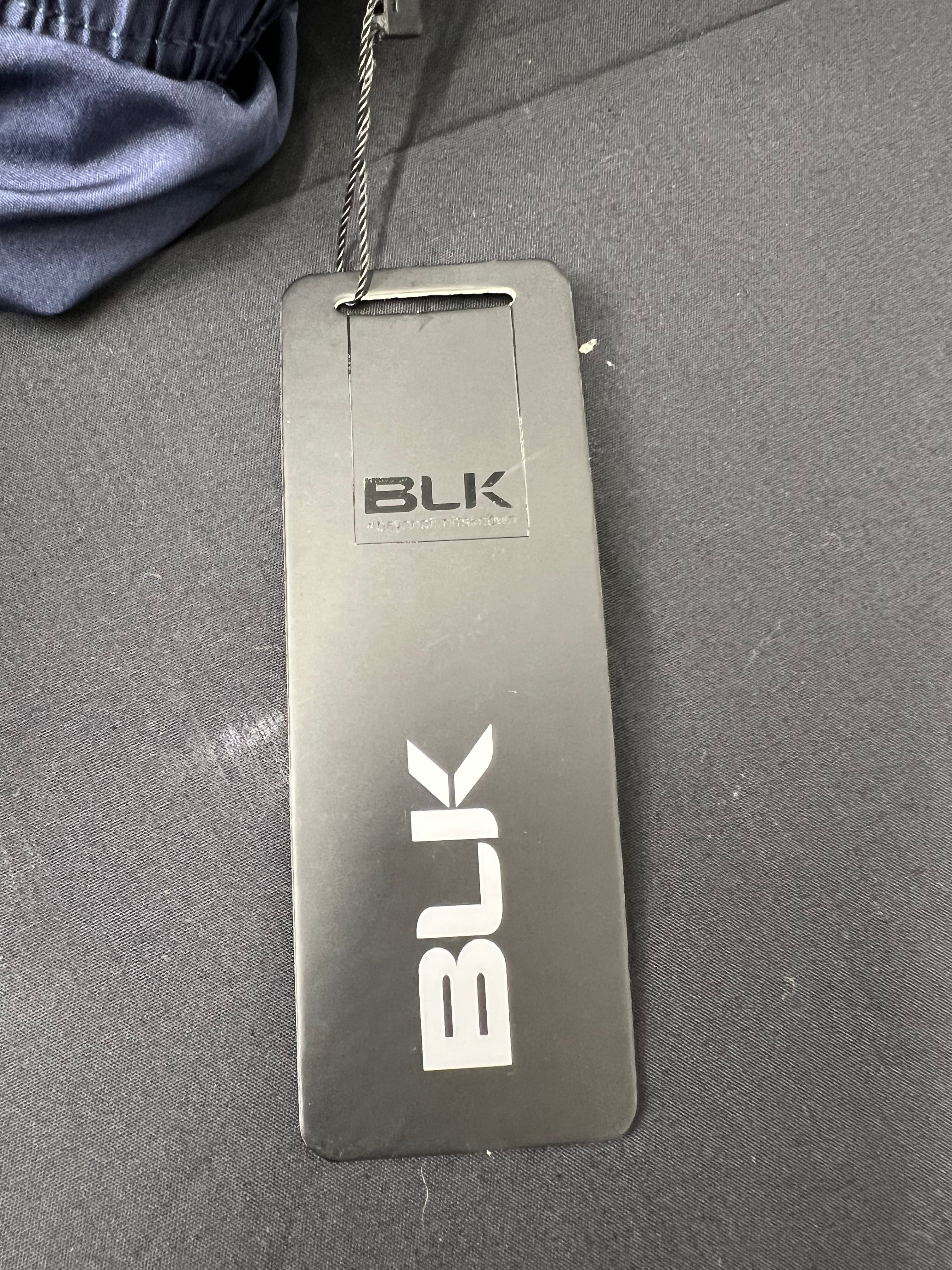 Close-up of BLK brand tag attached to navy blue tracksuit bottoms