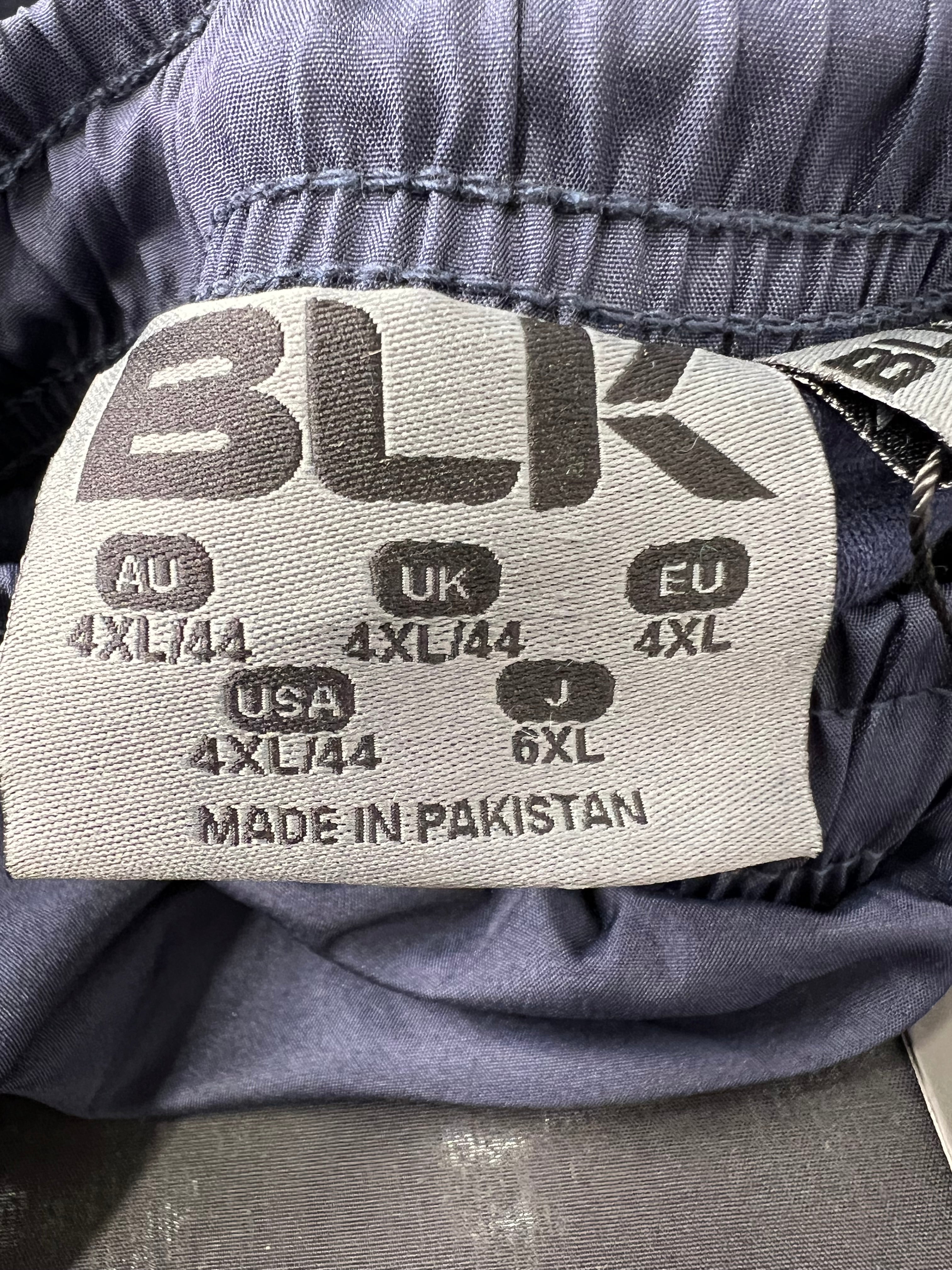 Close-up of size label inside men’s tracksuit bottoms showing 4XL size and made in Pakistan