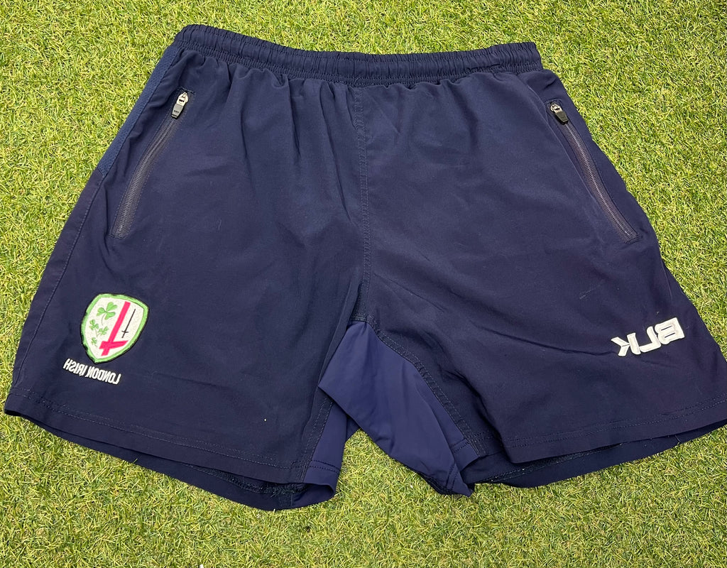 Front view of navy blue BLK London Irish sports shorts with zip pockets and embroidered team logo on left leg