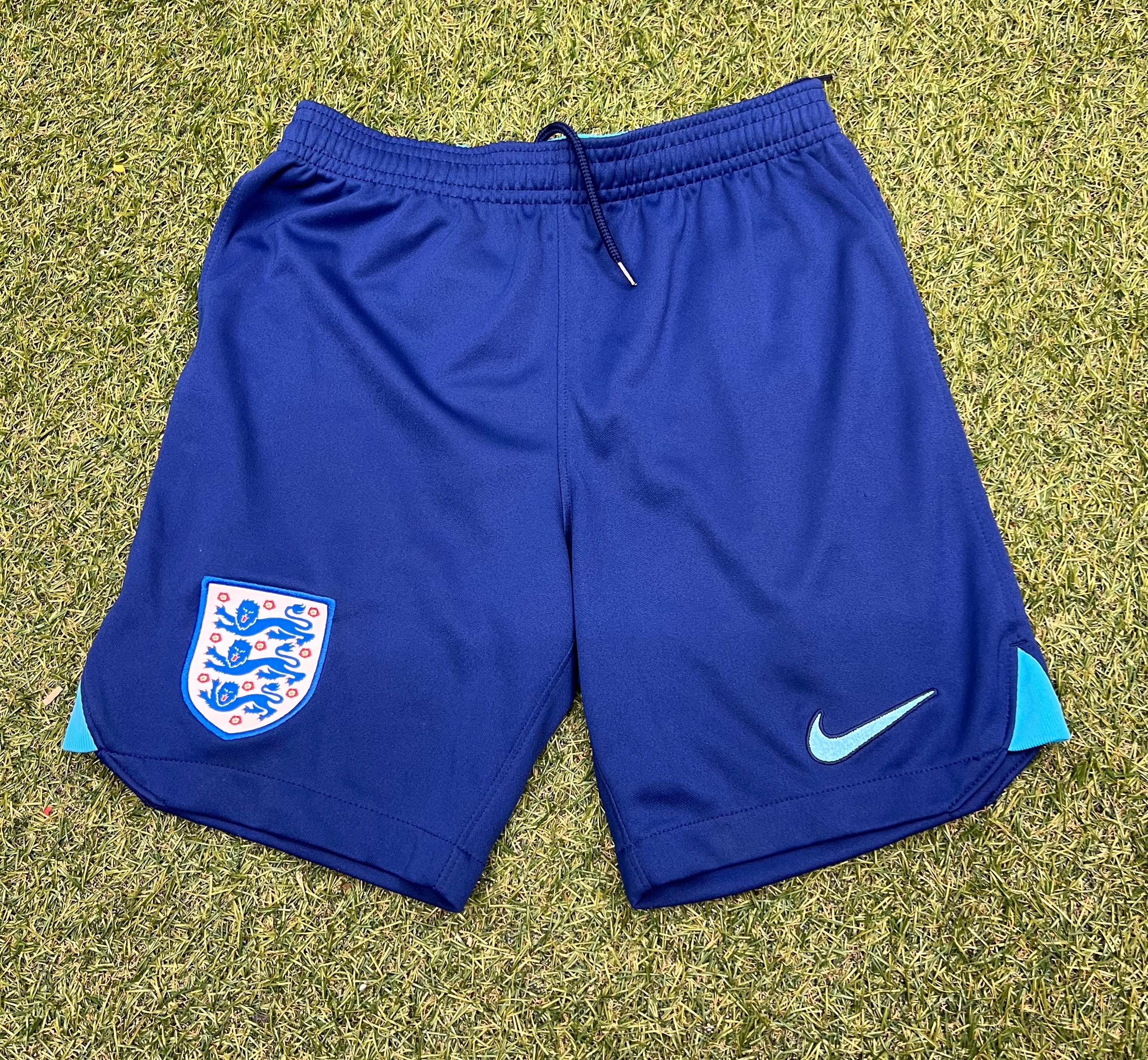 Front view of kids England blue football shorts with England crest and Nike logo