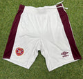 Front view of white and maroon Umbro Hearts FC football shorts with embroidered club crest and Umbro logo on grass background