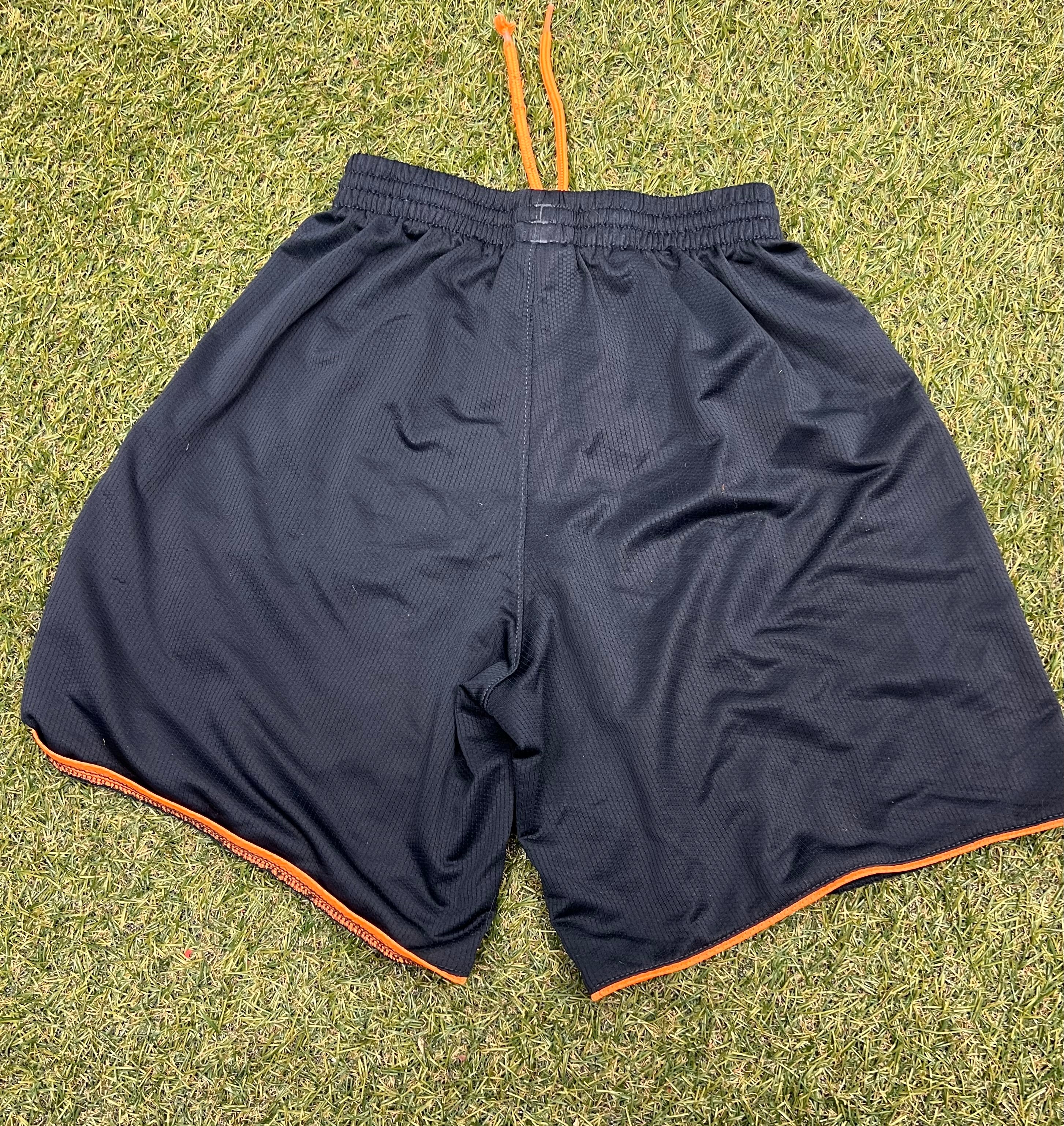 Back view of black kids adidas shorts with orange drawstring and orange hem detail