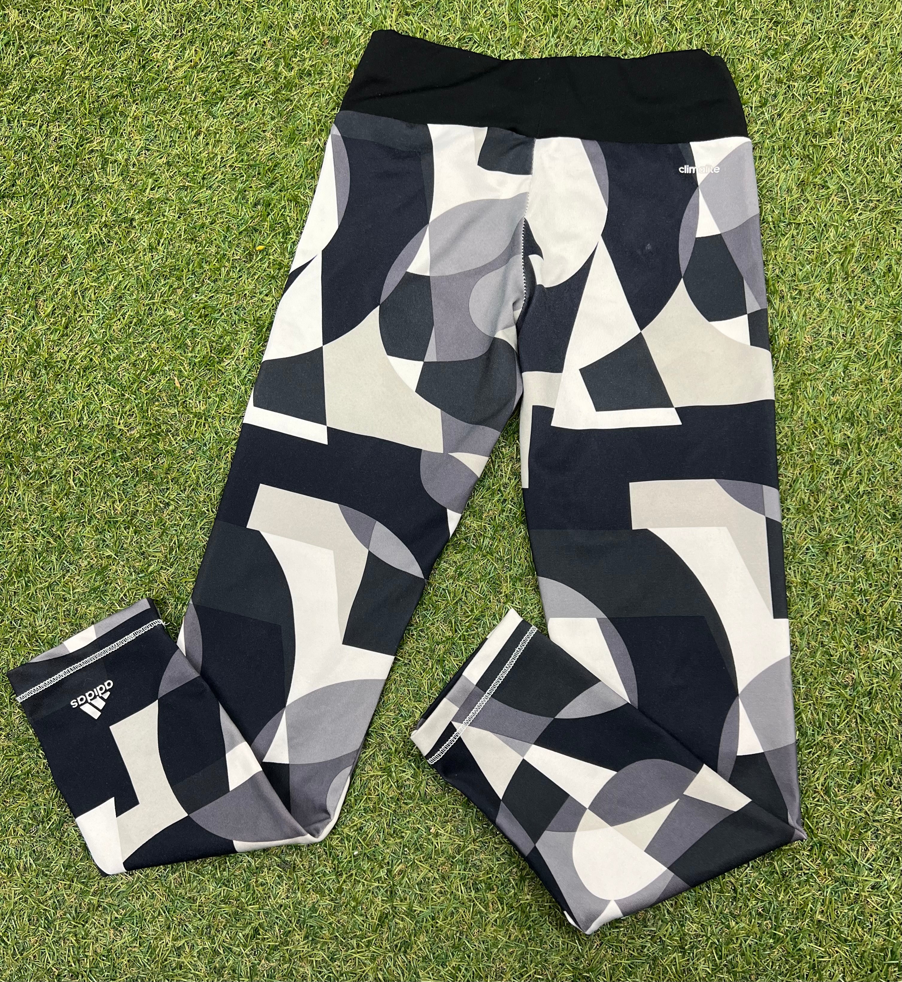 Back view of adidas kids leggings showing Climalite label and elastic waistband on grass