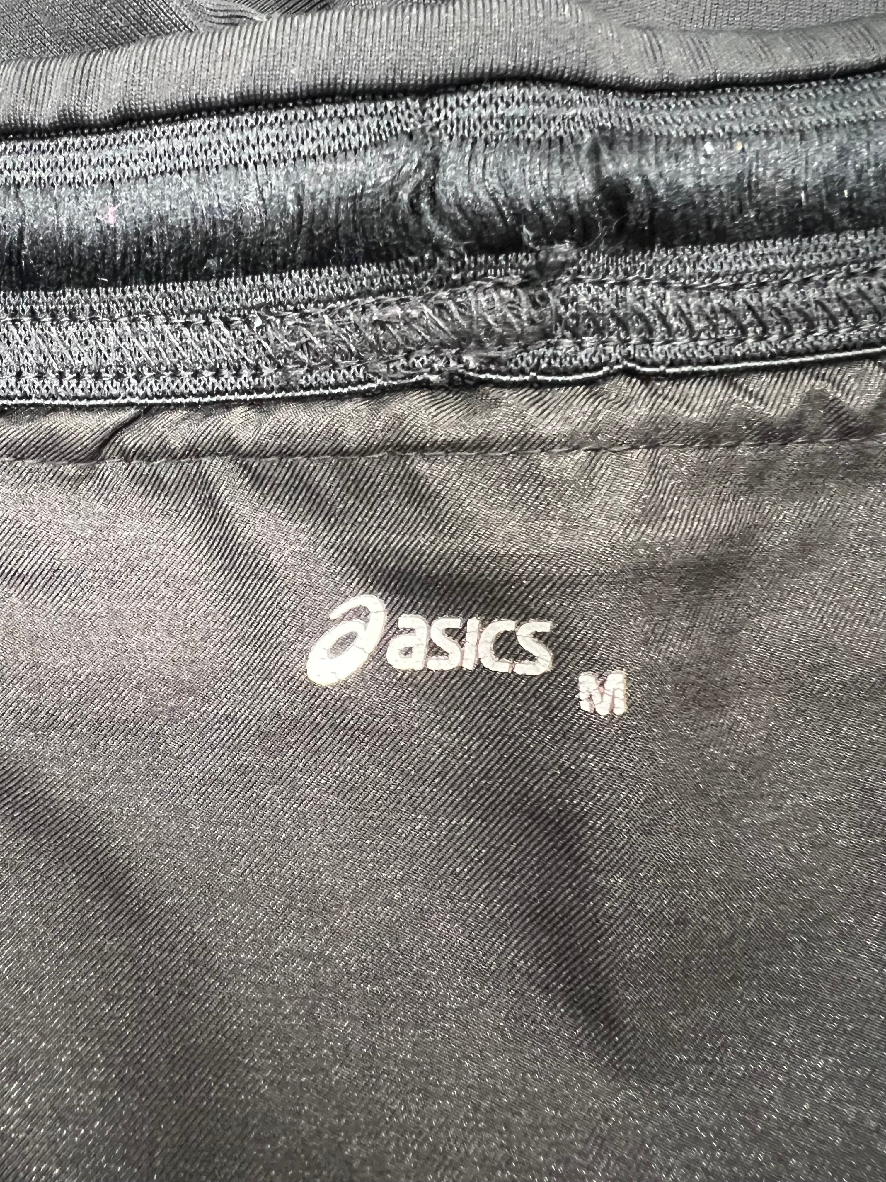 Close-up of Asics logo and size label inside black cropped leggings
