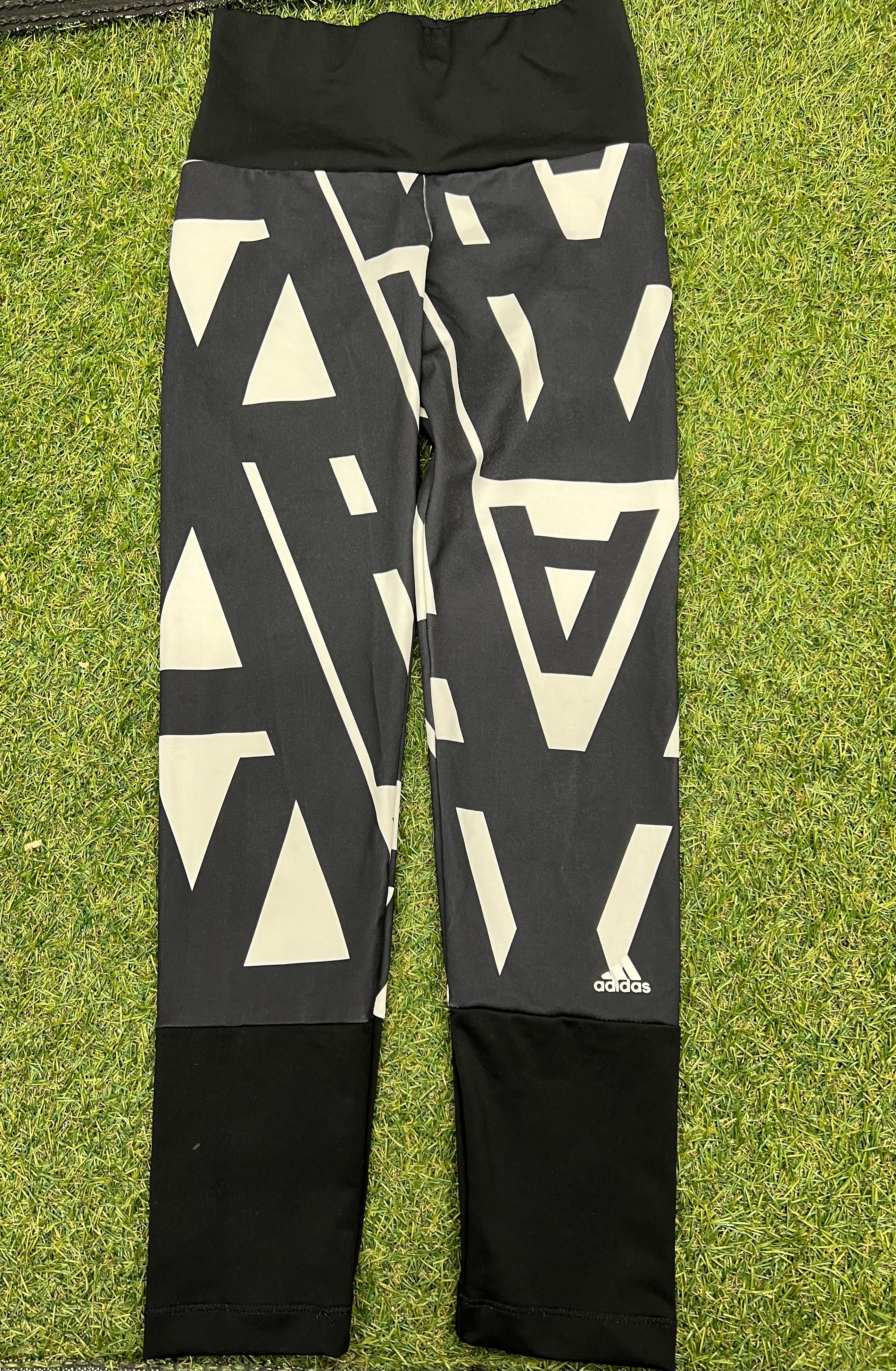 Front view of Adidas kids leggings with black waistband and geometric black and white pattern on legs