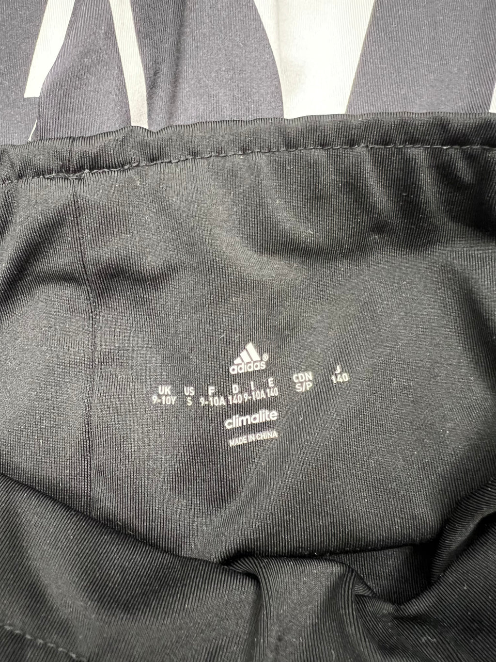 Close-up of Adidas Climalite label inside the black elastic waistband, size 9-10 years