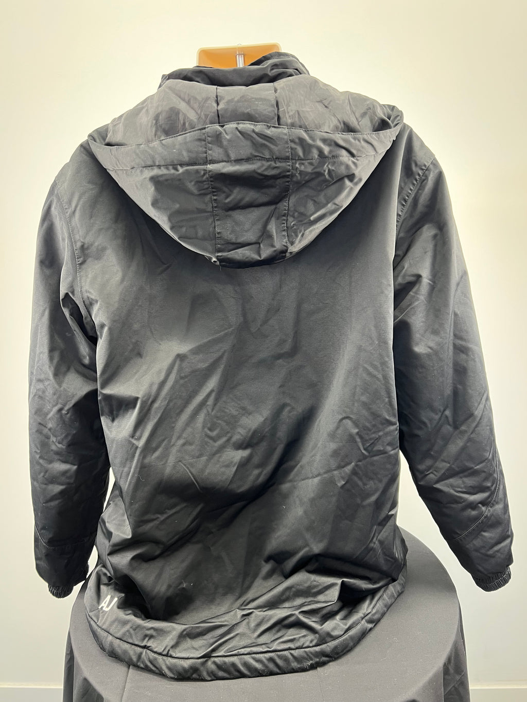 Back view of men’s black hooded jacket showing hood and elasticated hem