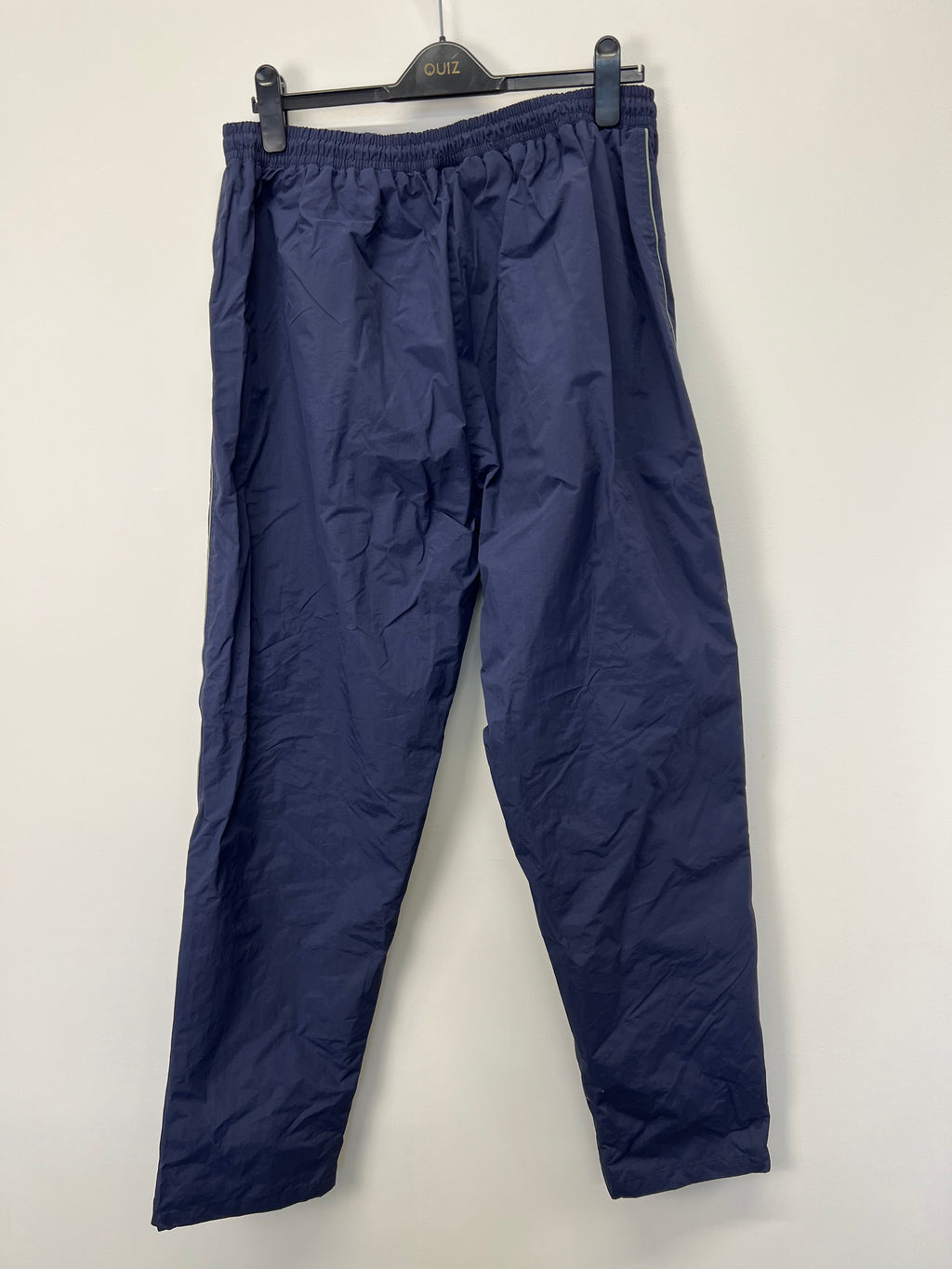 Rear view of solid dark blue tracksuit bottoms showcasing simple design and elastic waistband
