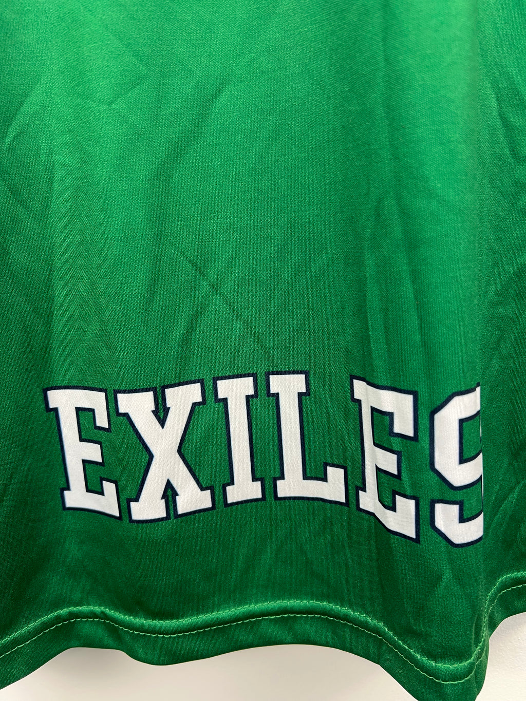 Close-up of Exiles printed text on lower back of London Irish rugby training top in green