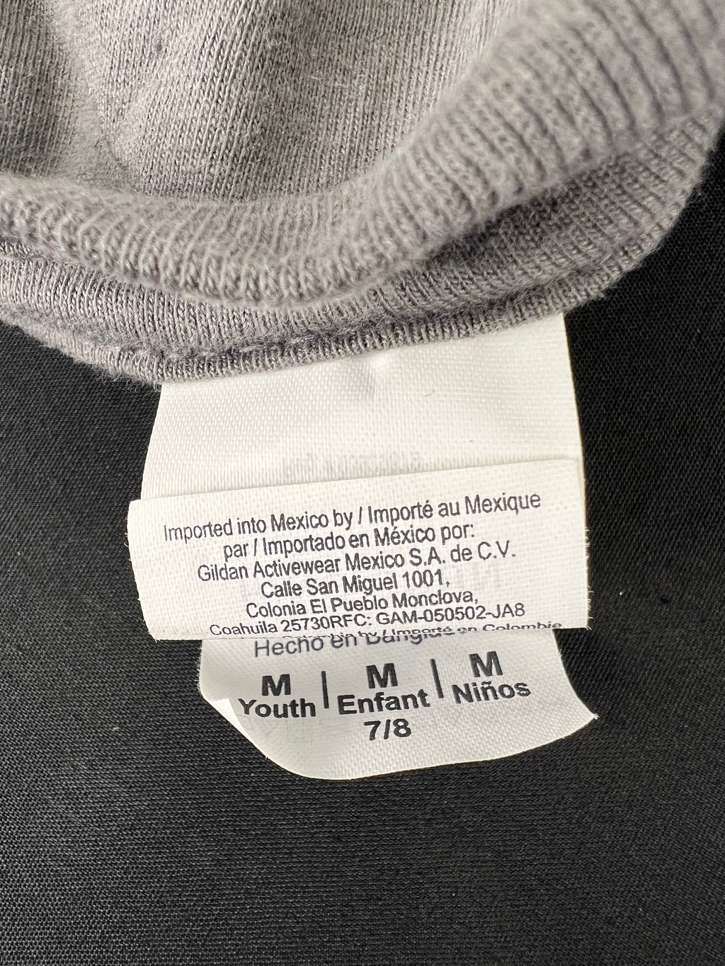 Close-up of sizing and manufacturing label inside grey kids t-shirt, indicating size 7/8