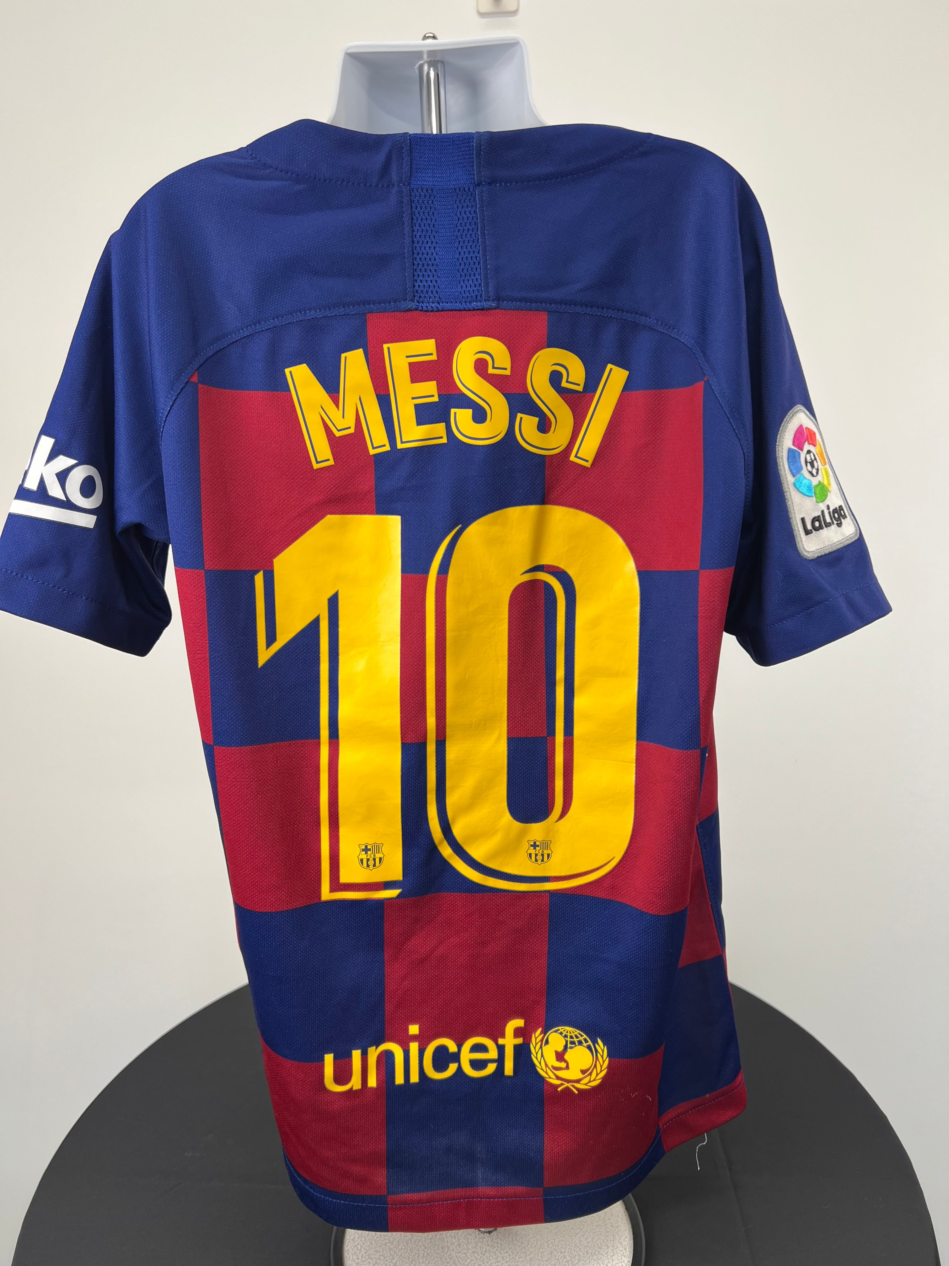 Back view of kids FC Barcelona football shirt showing Messi name and number 10 printed in yellow with La Liga patch on the sleeve