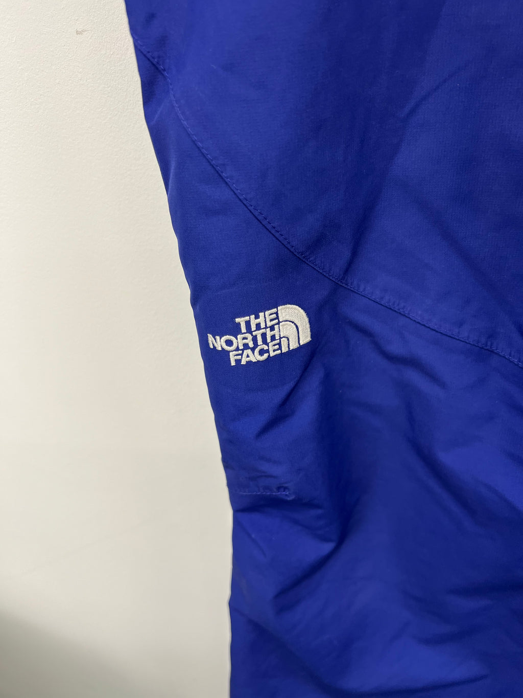 Embroidered The North Face logo on left leg of blue ski trousers