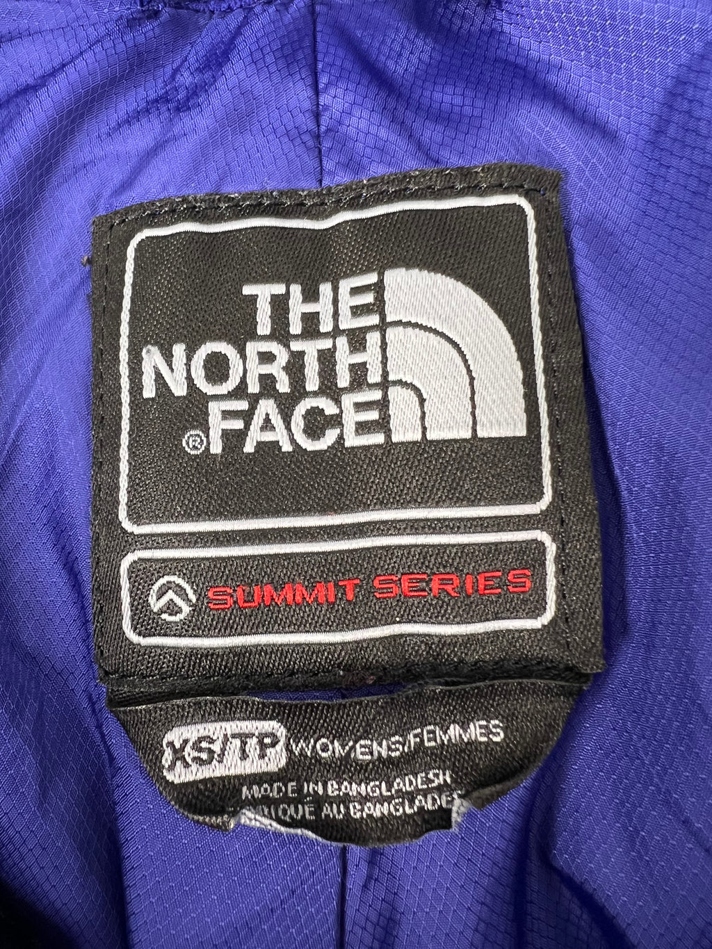 Close-up of size and brand label inside blue The North Face Summit Series ski trousers