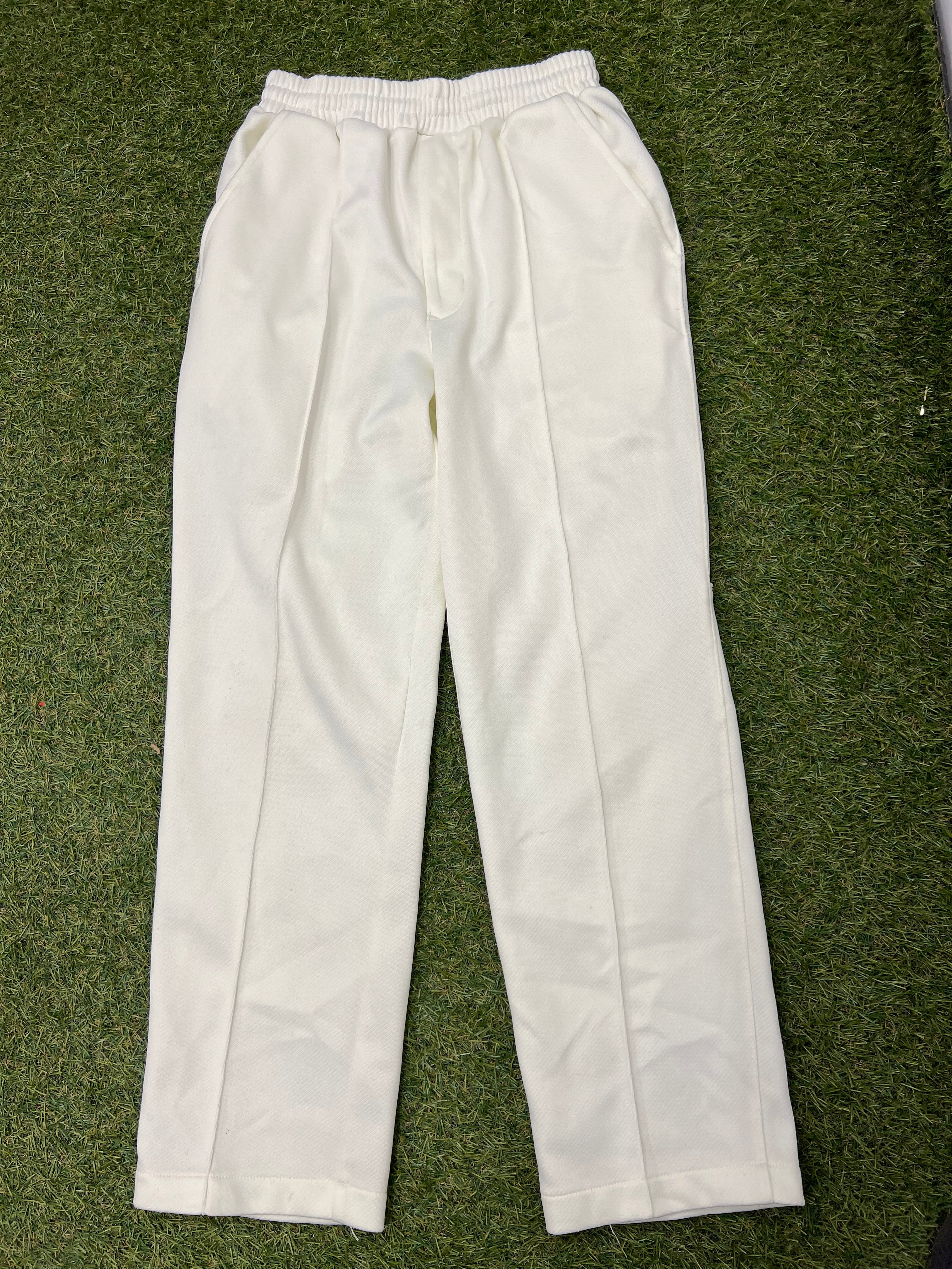 Front view of white Kids Salamander cricket trousers size S on grass