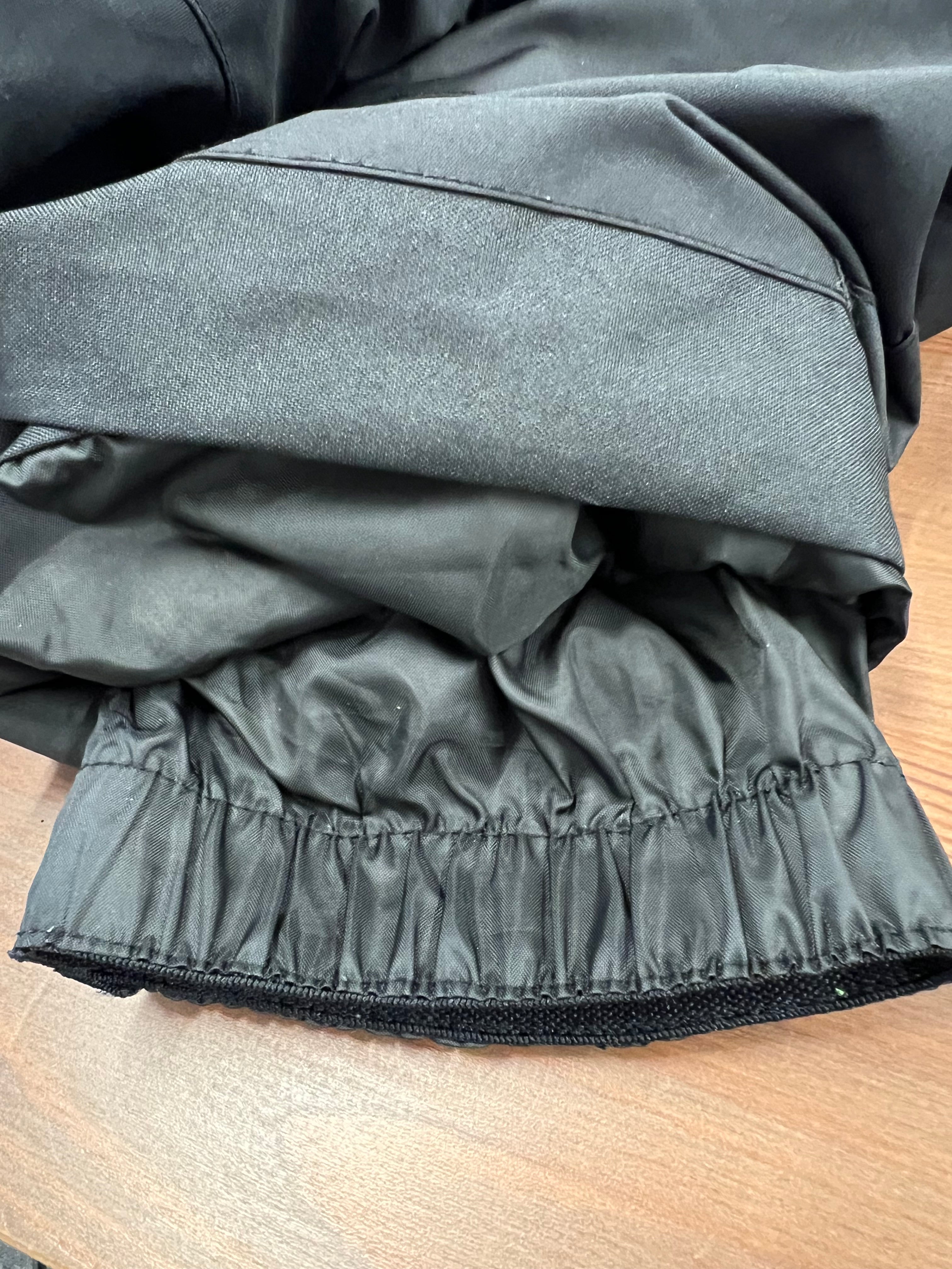 Detail of elasticated ankle cuff of black ski trousers on wooden surface