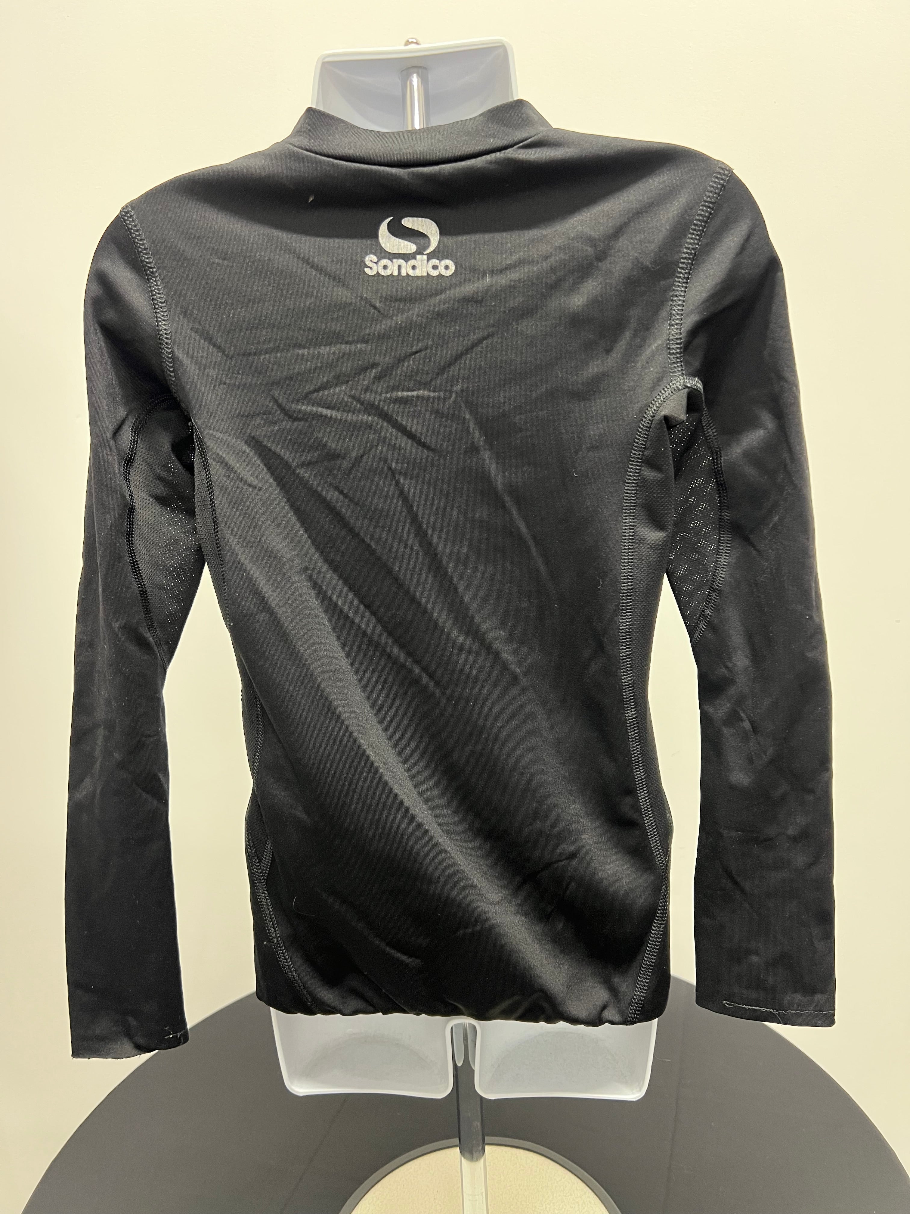 Back view of black kids Sondico base layer top showing logo and ventilation panels on arms