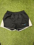 Front view of black Bionix rugby shorts with white side panels on grass