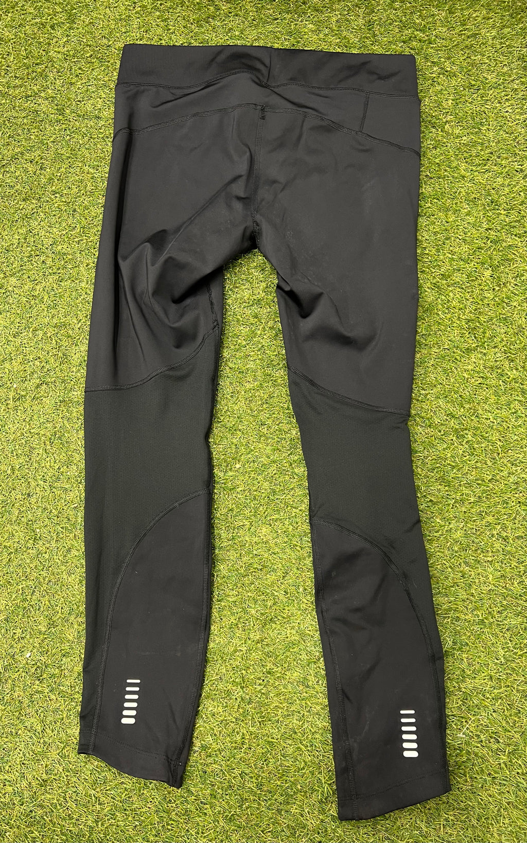 Back view of Under Armour women's black compression leggings showing reflective detailing on lower legs