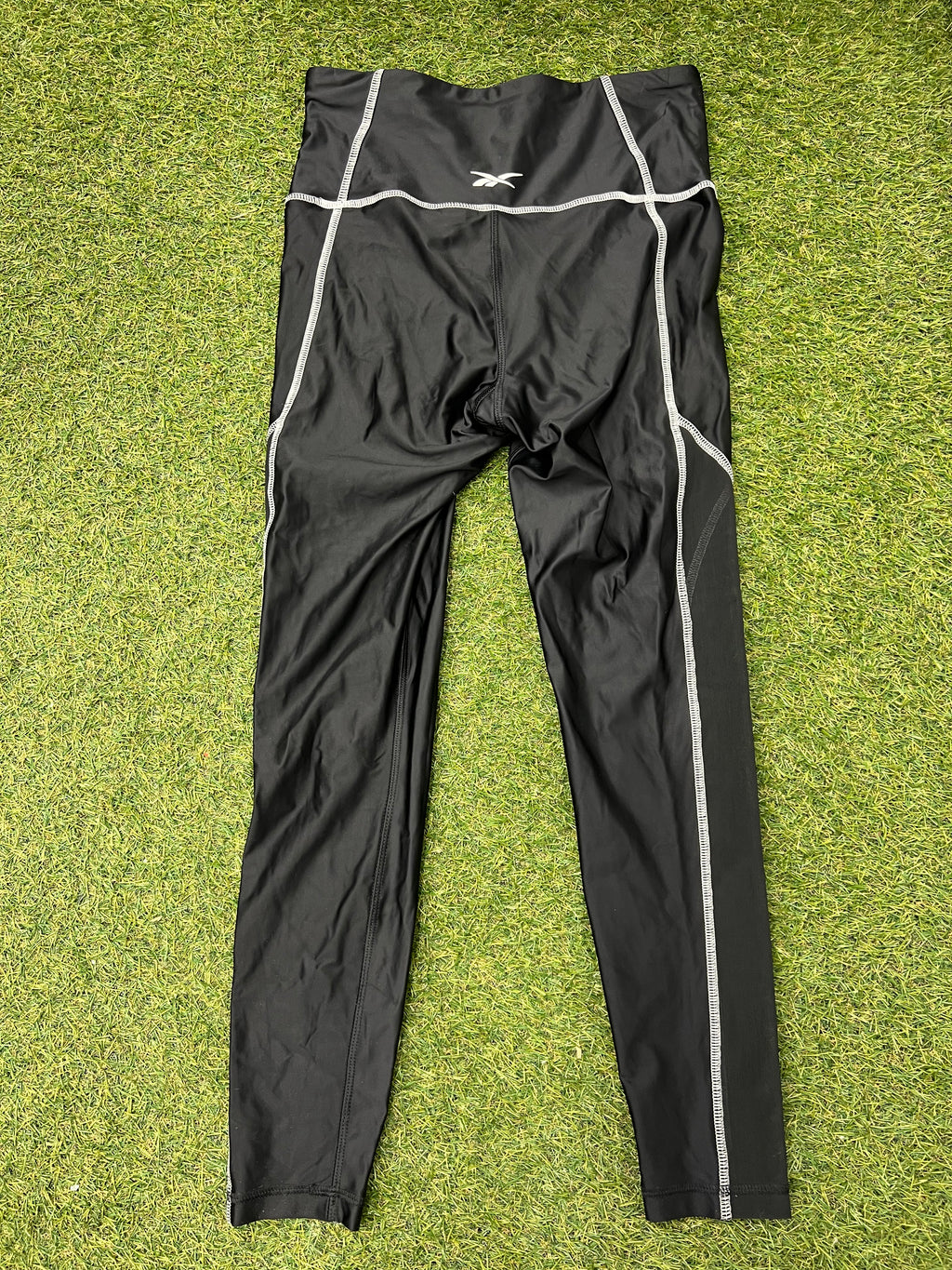 Back view of black Women’s Reebok Speedwick leggings showing Reebok logo on waistband and side mesh panels