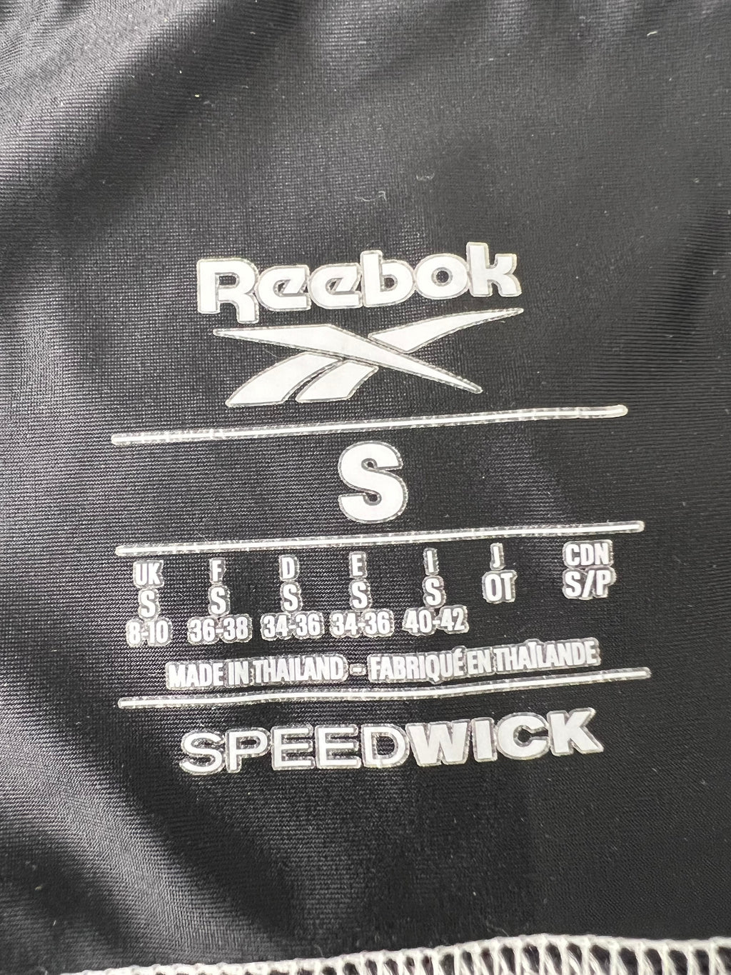 Close-up of size label inside Women’s Reebok Speedwick leggings showing size S and made in Thailand