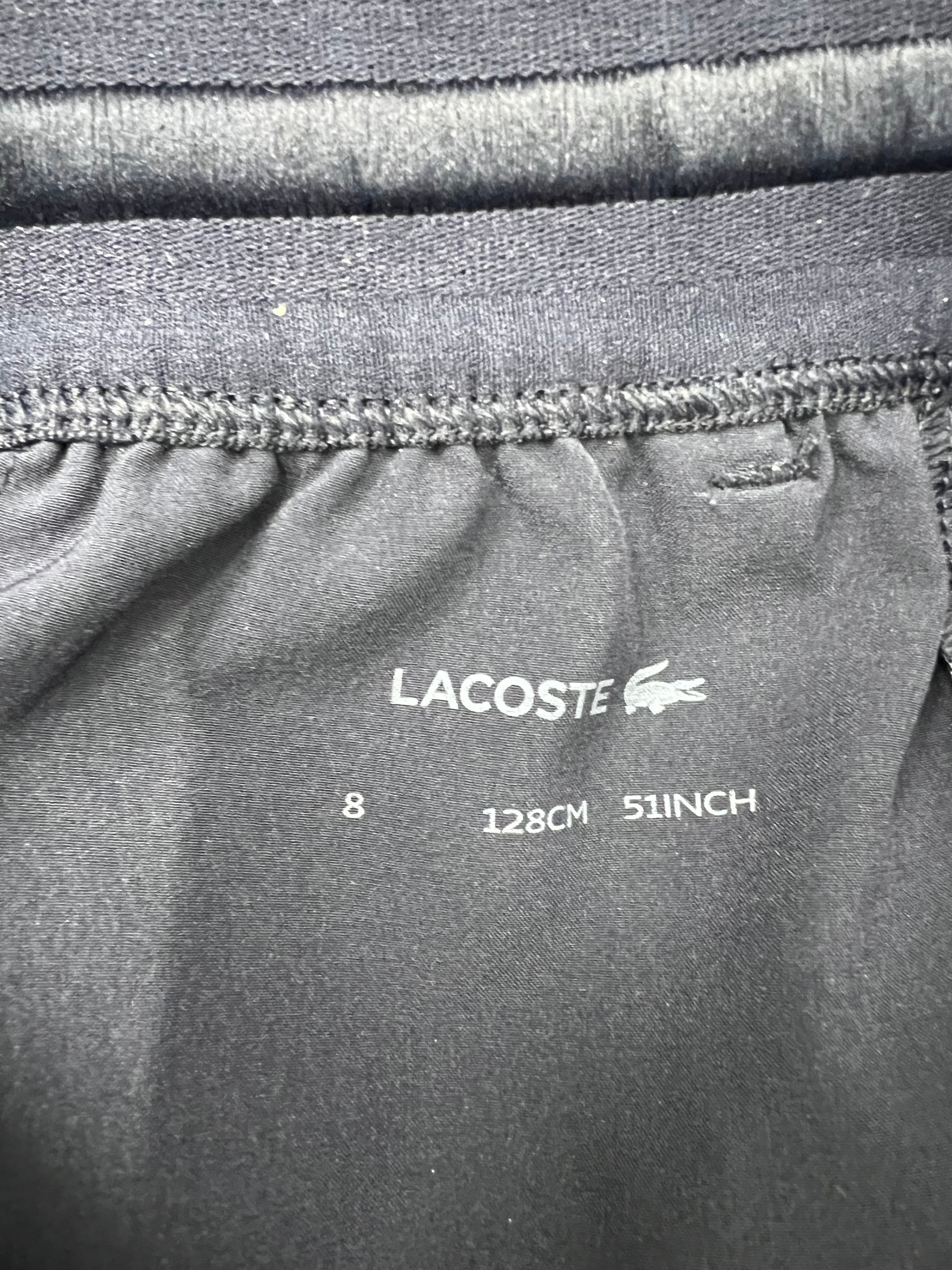 Close-up of Lacoste label inside black sports shorts indicating size 8 for kids