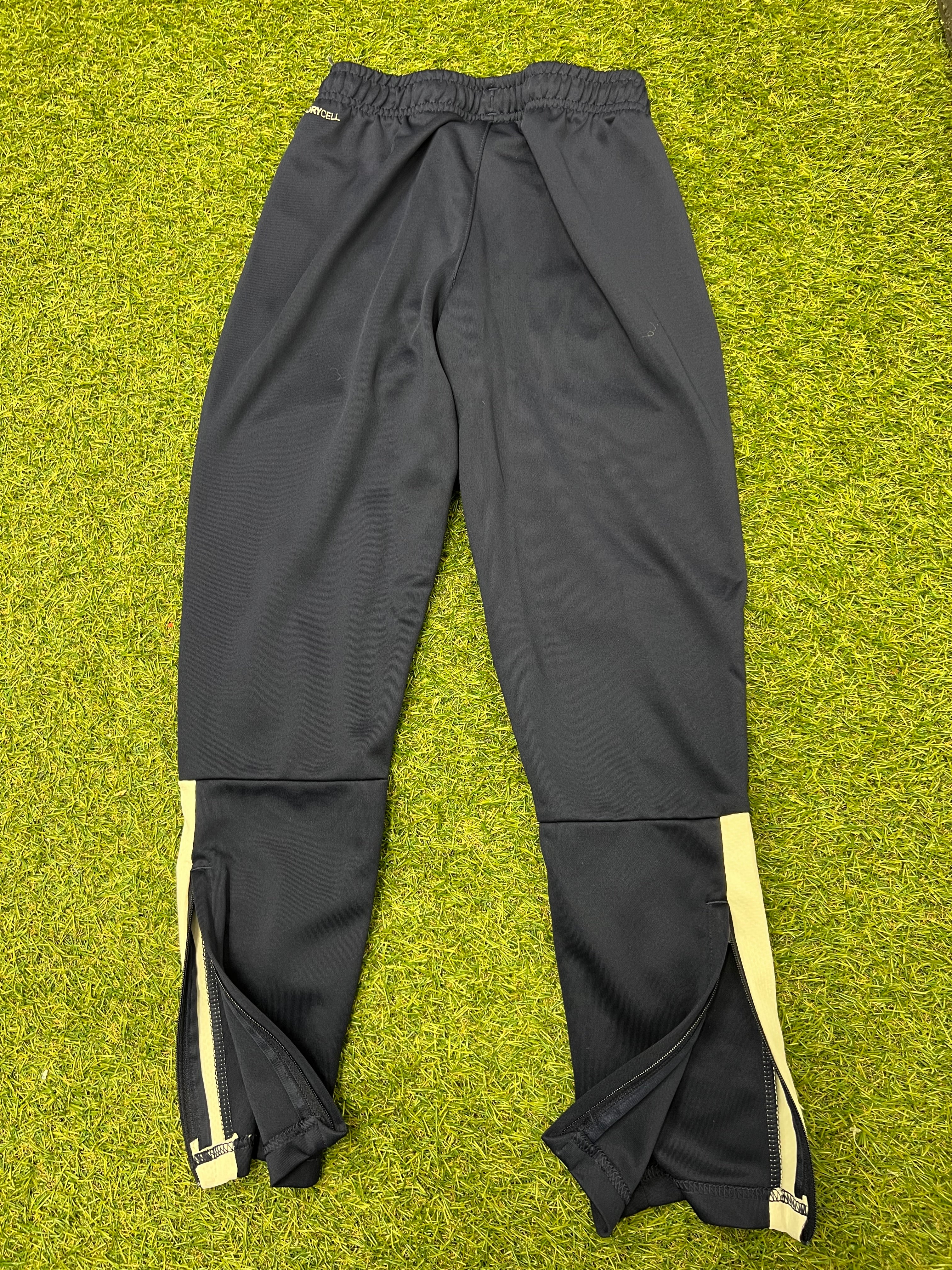 Back view of navy blue Puma kids tracksuit bottoms showing ankle zips and light side stripes