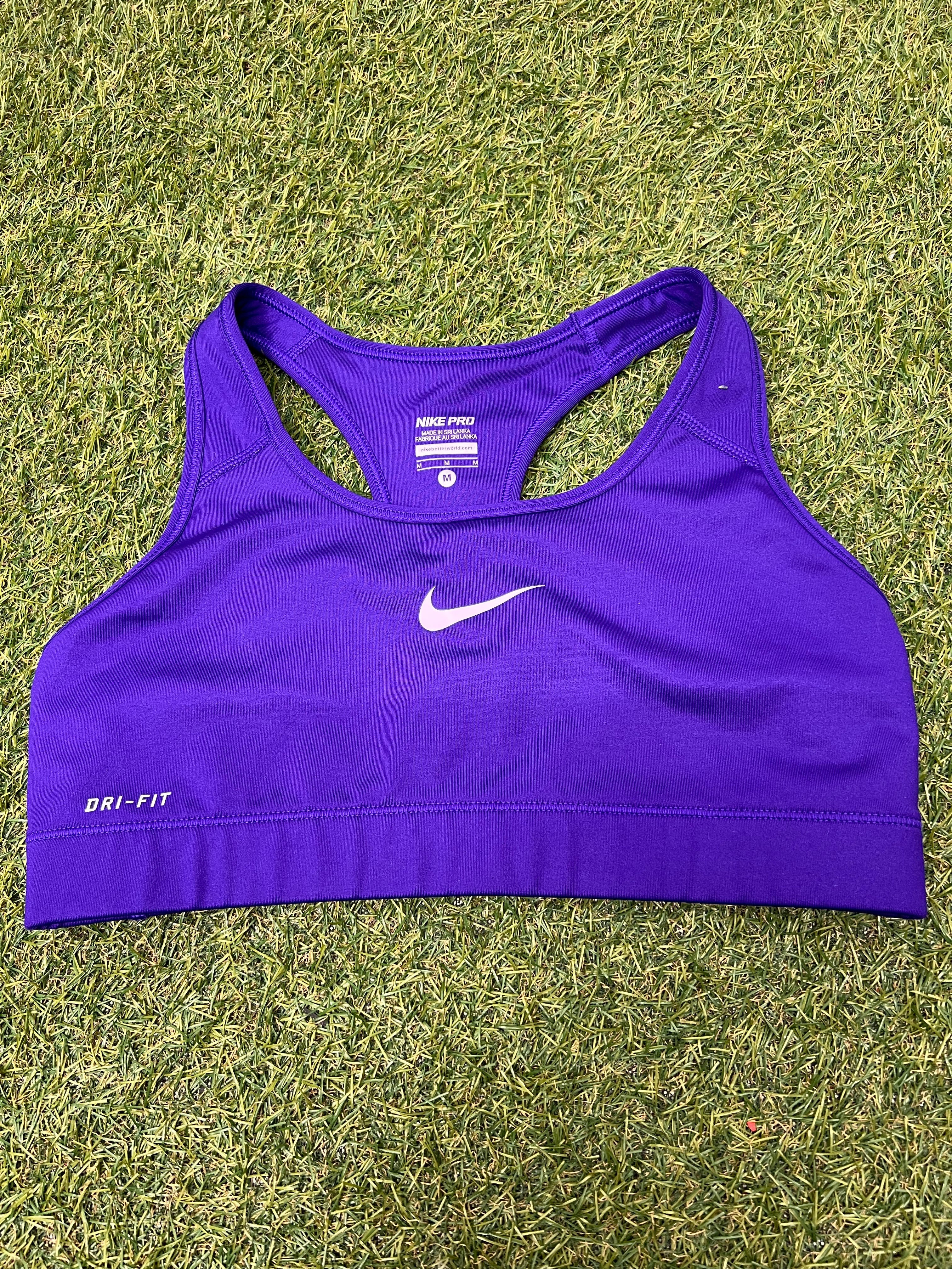 Front view of Nike Pro Dri-FIT purple sports bra laid flat on grass