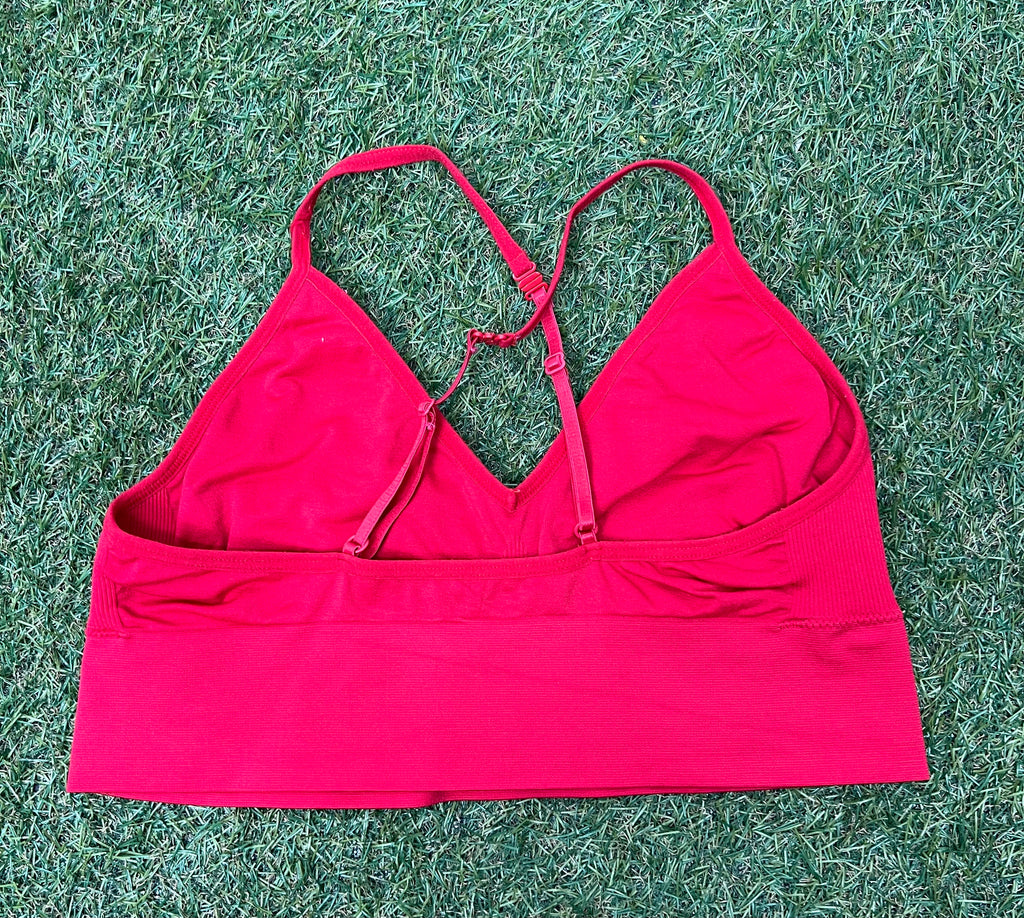 Back view of red Reebok sports bra top with crossed adjustable straps visible against grass